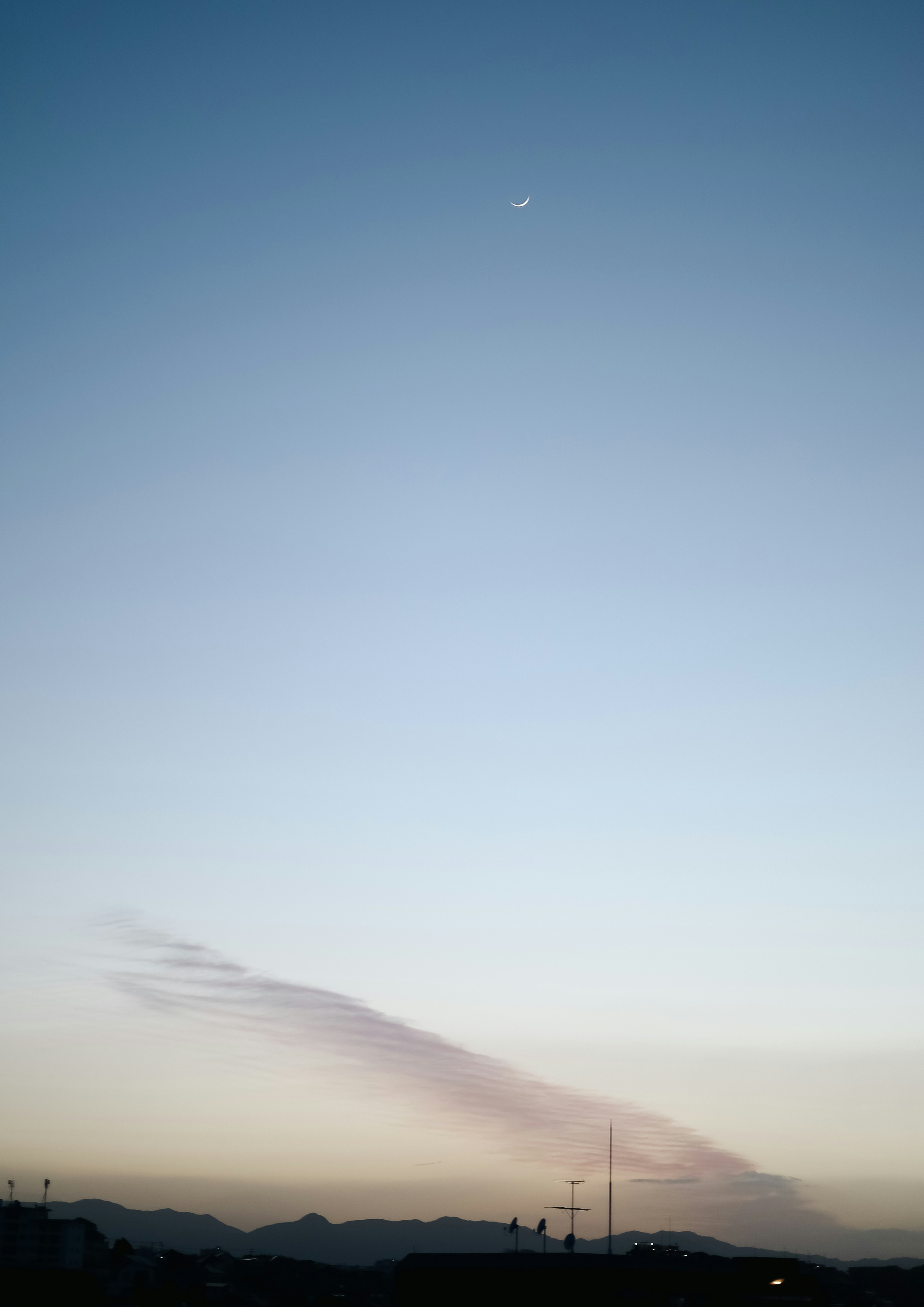 夕暮れの空に浮かぶ月と雲の流れ