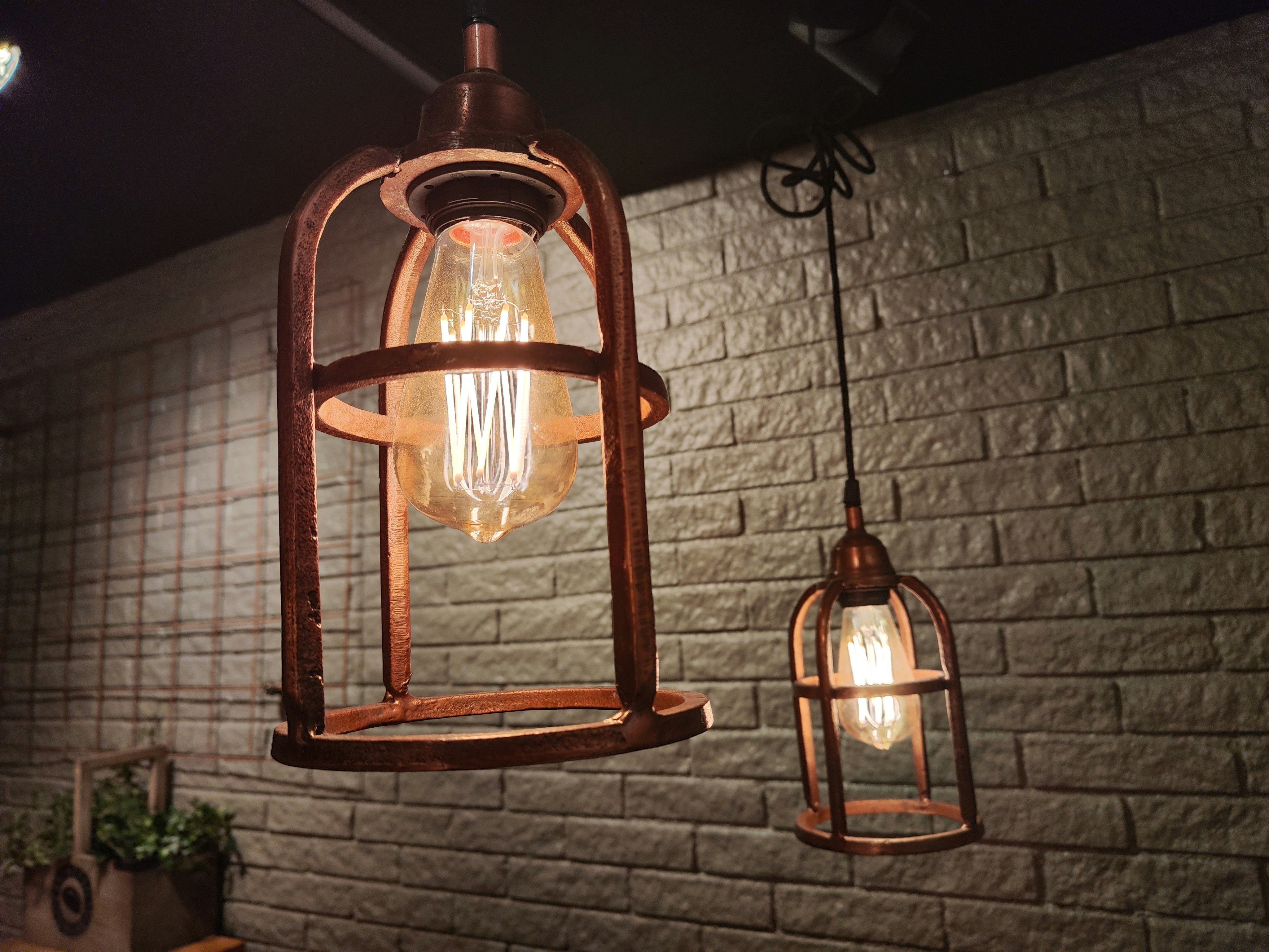 antique-style pendant lights hanging in a brick-walled cafe space