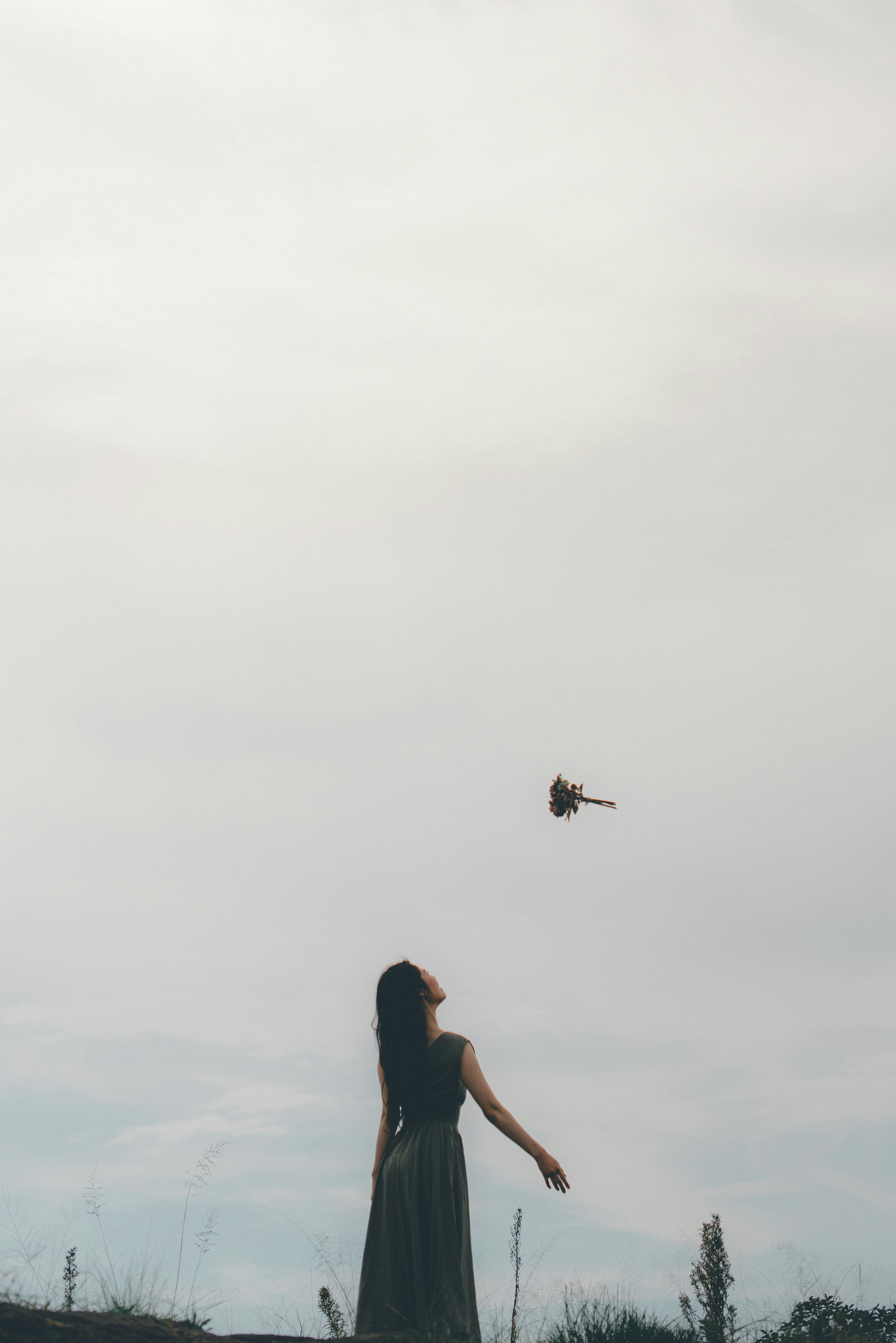 霧の空の下で風に揺れる緑のドレスの女性
