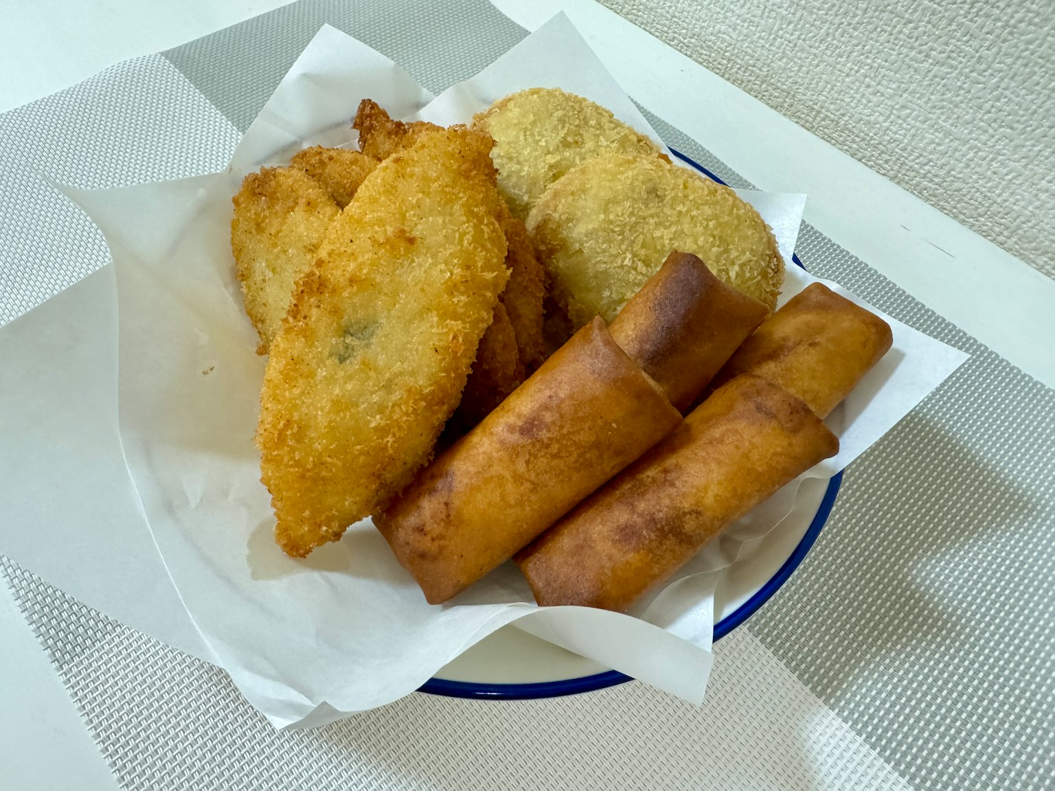 一盘各式炸食，包括春卷和裹面包屑的鱼