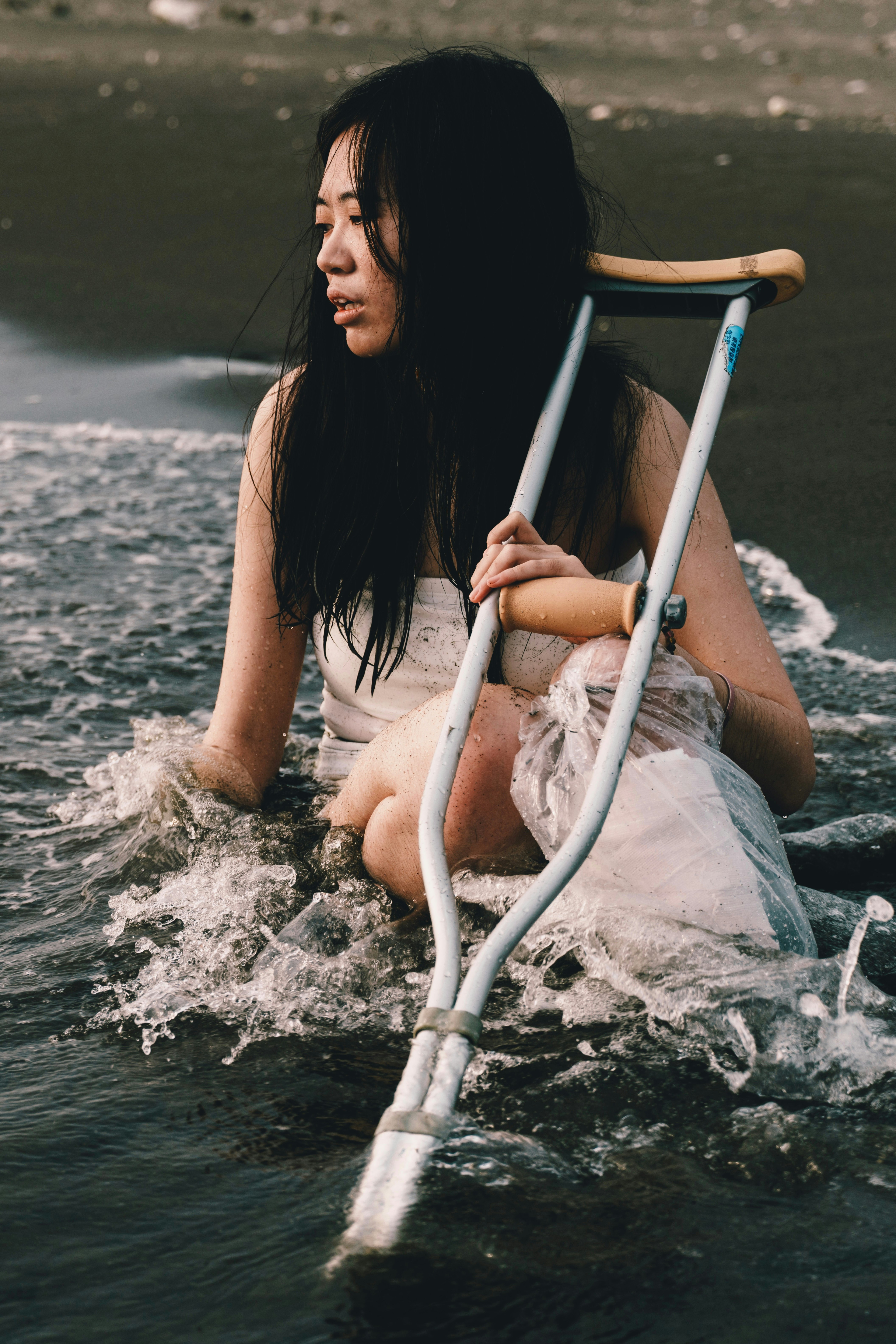 海岸で水しぶきを浴びながら海水に触れる女性