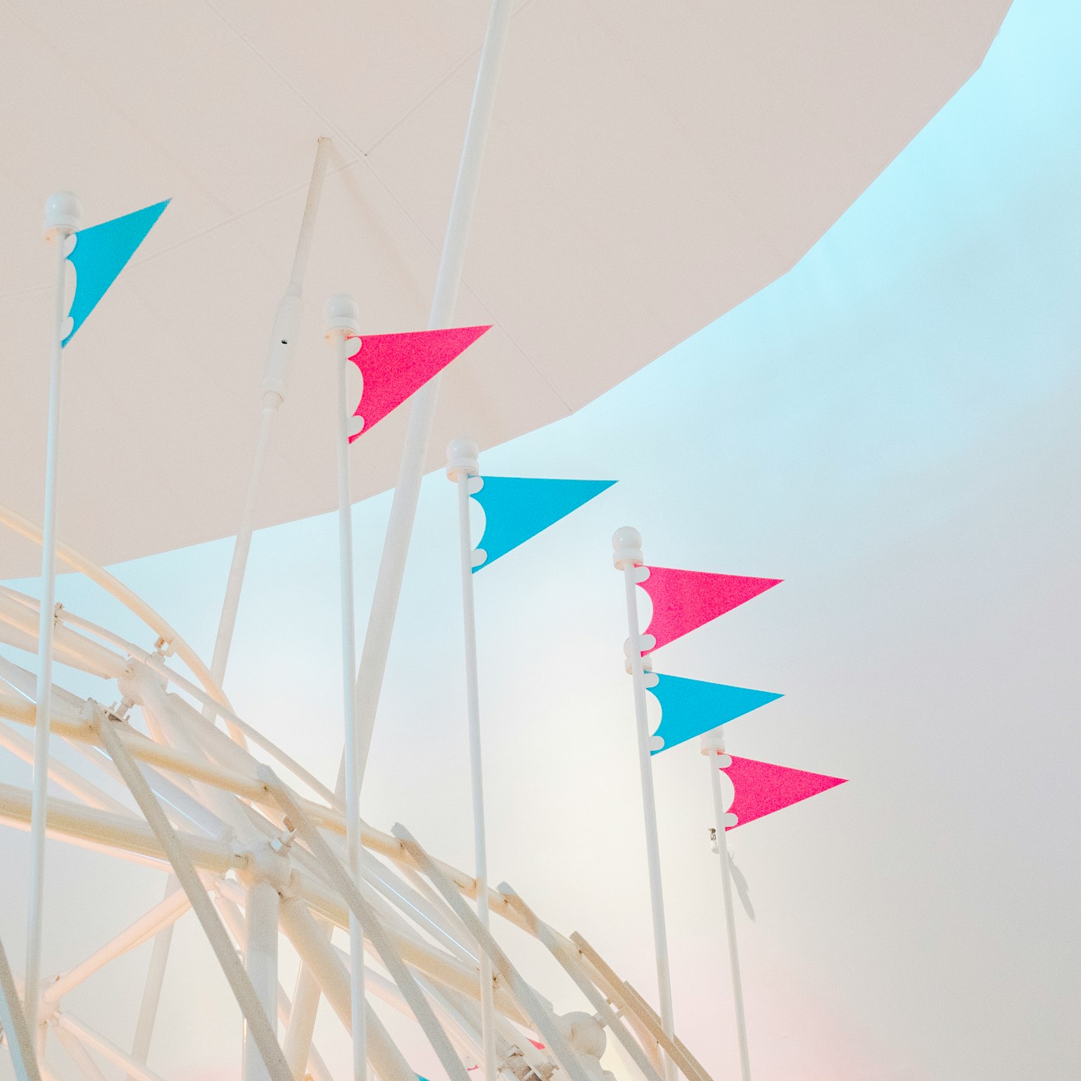Kunstinstallation mit kleinen blauen und rosa Fahnen vor weißem Hintergrund