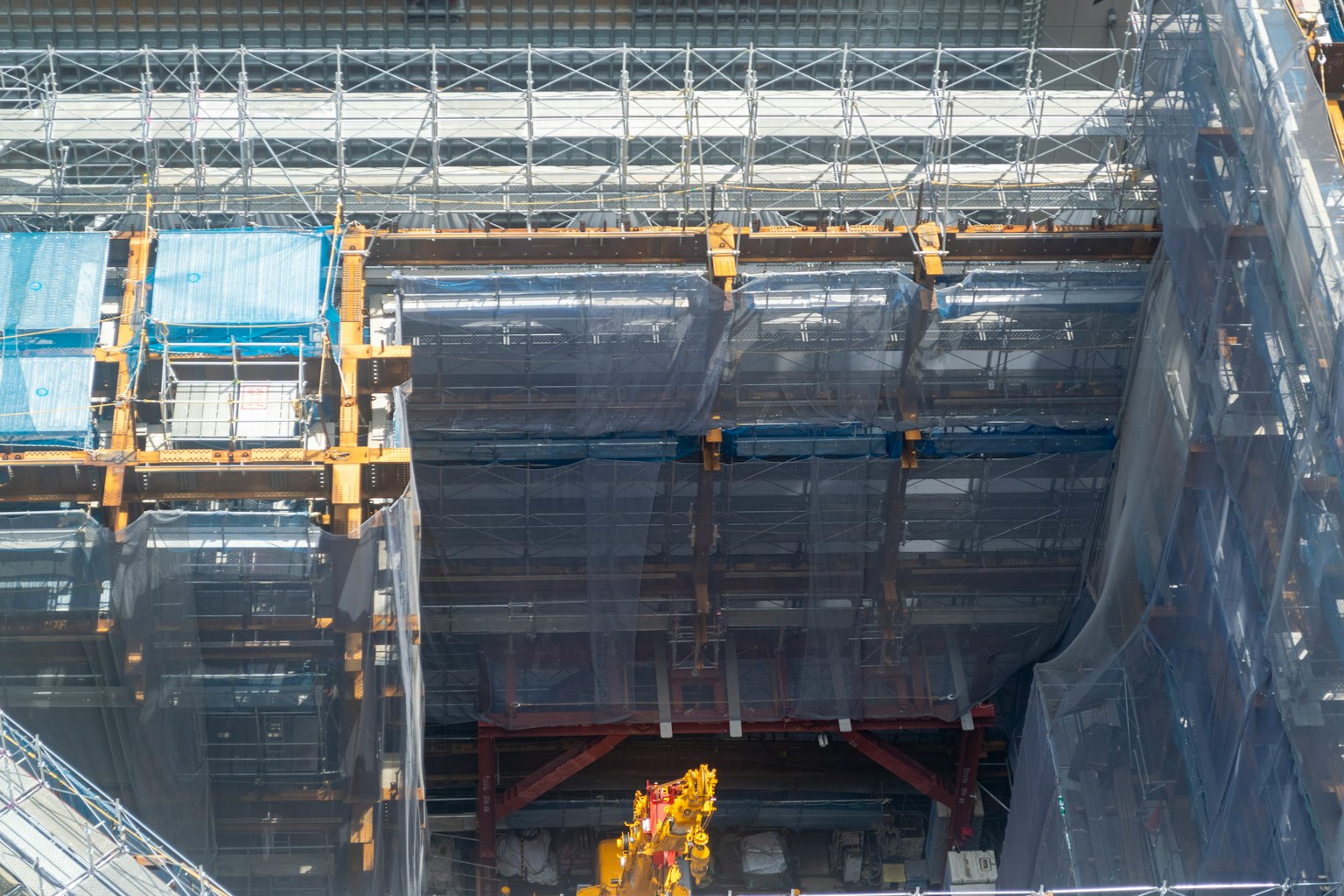 Vista di un cantiere con teli blu e struttura metallica visibile