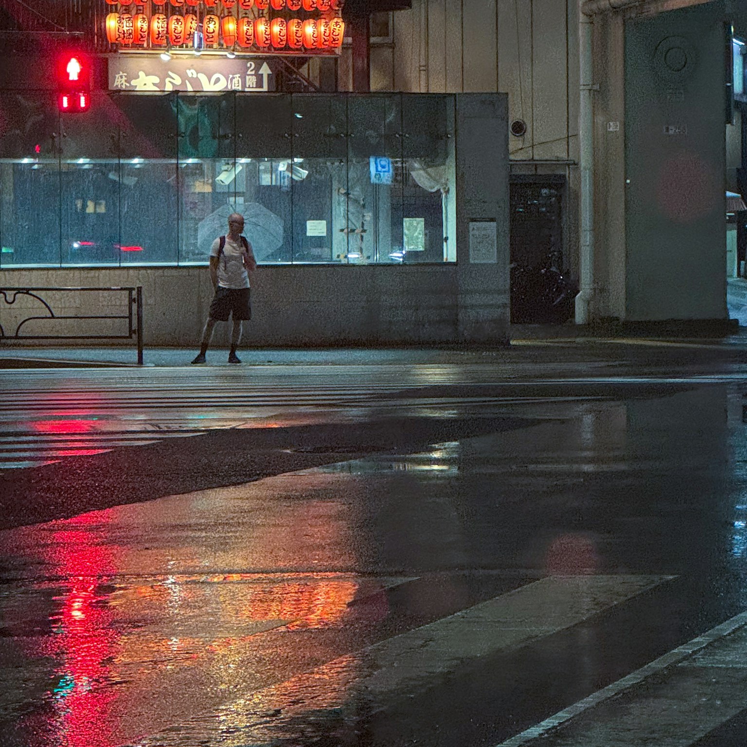 Une silhouette se tenant à un coin de rue mouillé avec des reflets de lumières néon