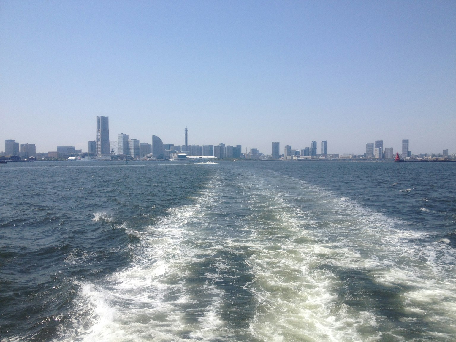 Blick auf die Bucht von Tokio mit einer Skyline von Wolkenkratzern und Bootswehen
