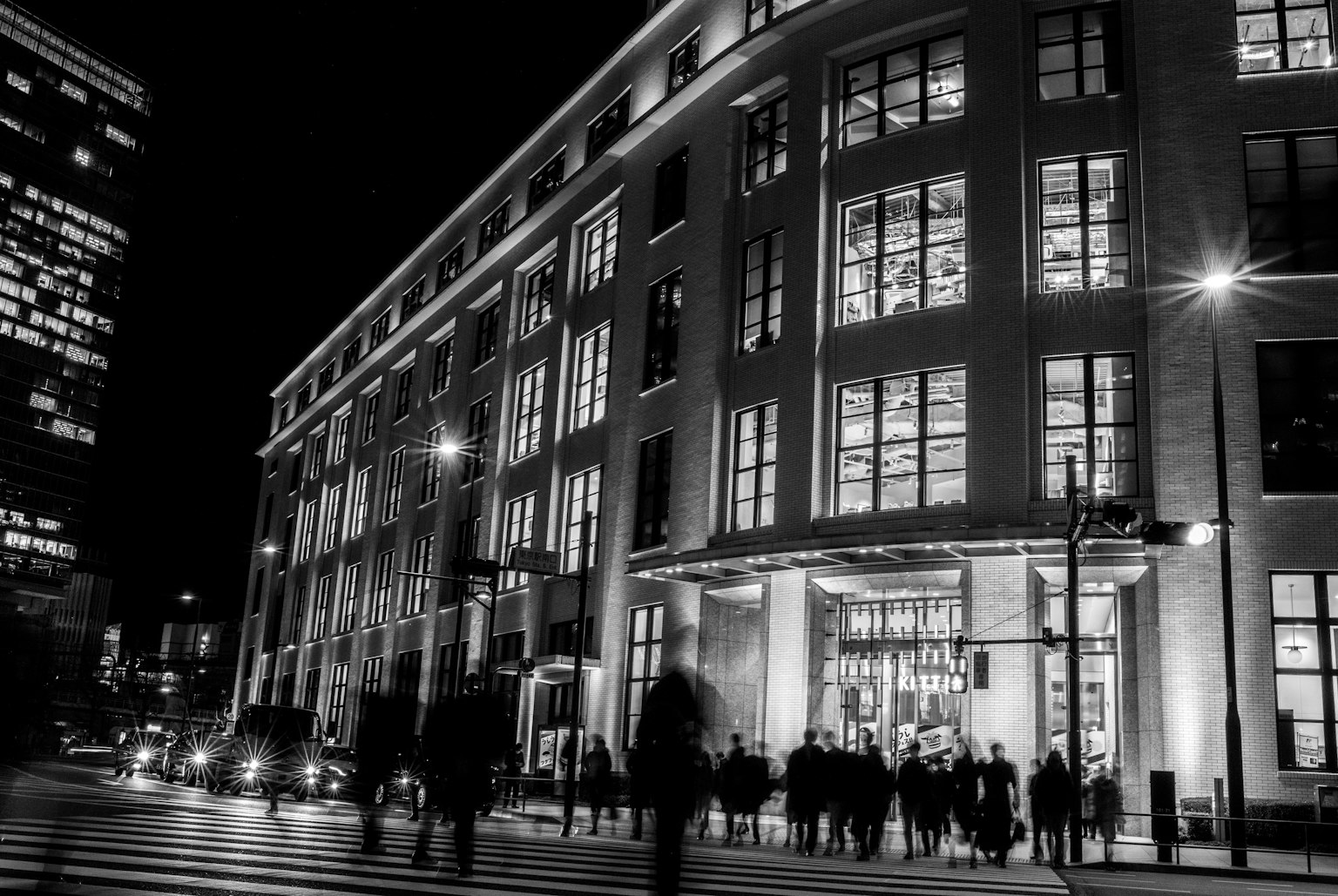 Modern building in urban night scene with silhouettes of people