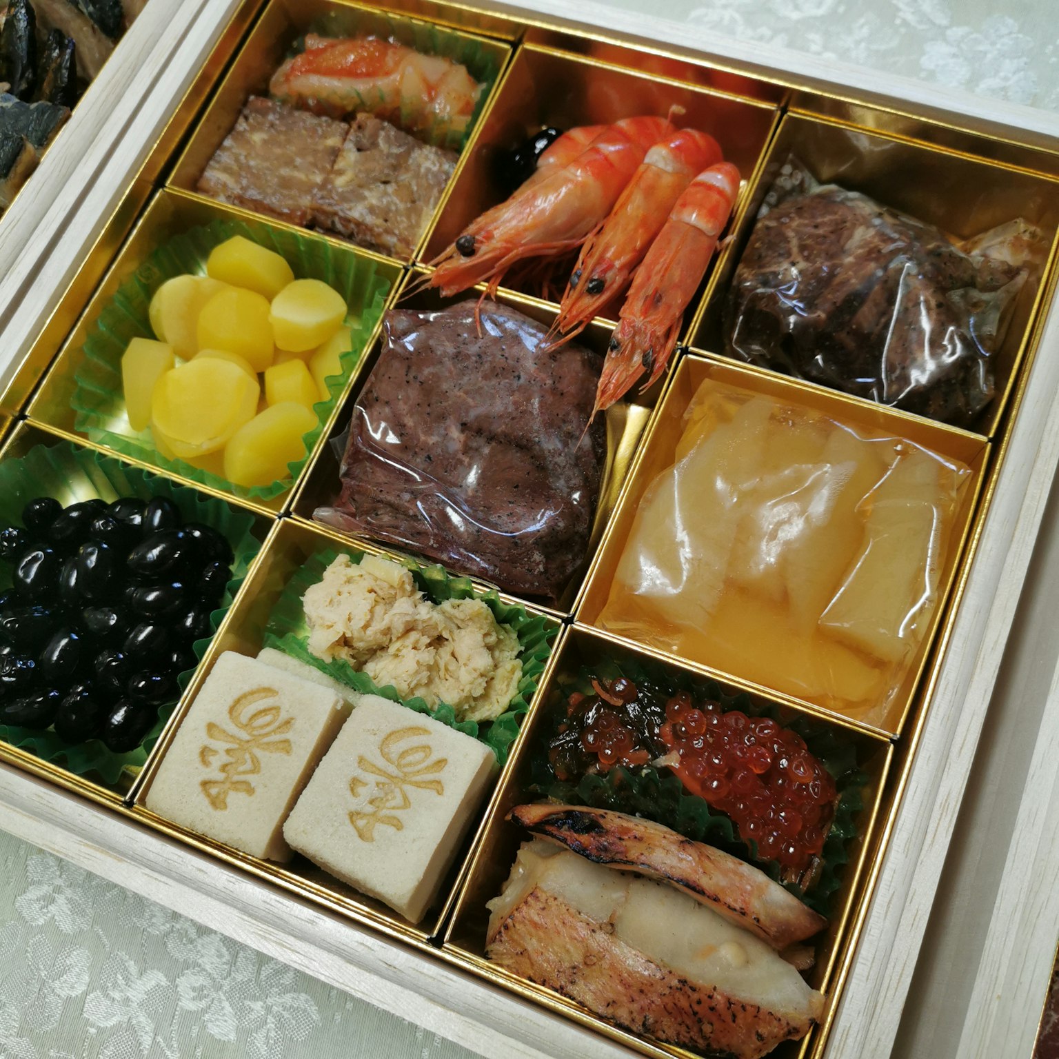 Cuisine Osechi joliment présentée Neuf compartiments remplis de plats Crevettes fraîches et haricots noirs