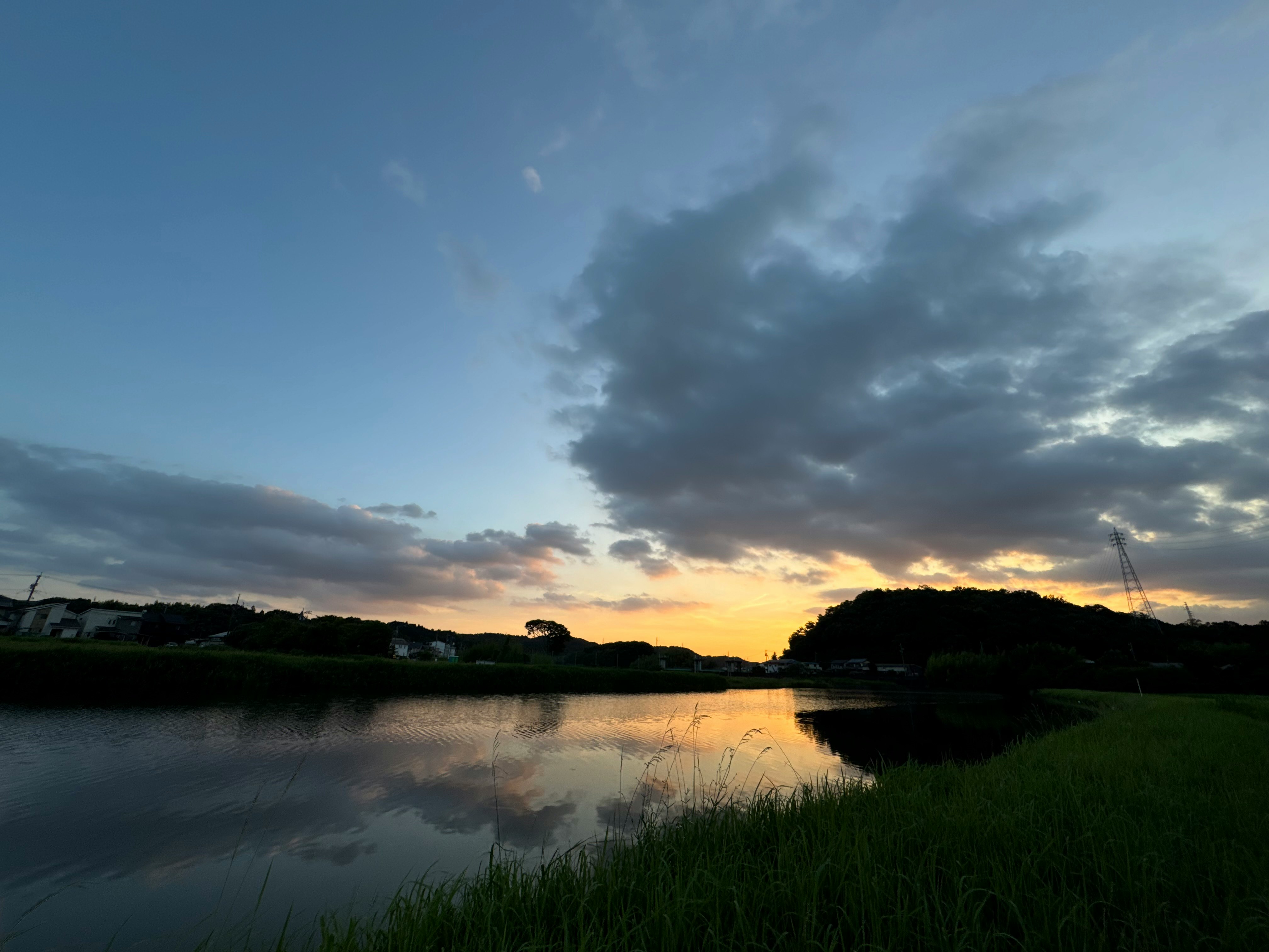 夕暮れの湖畔に広がる水面と草地の風景