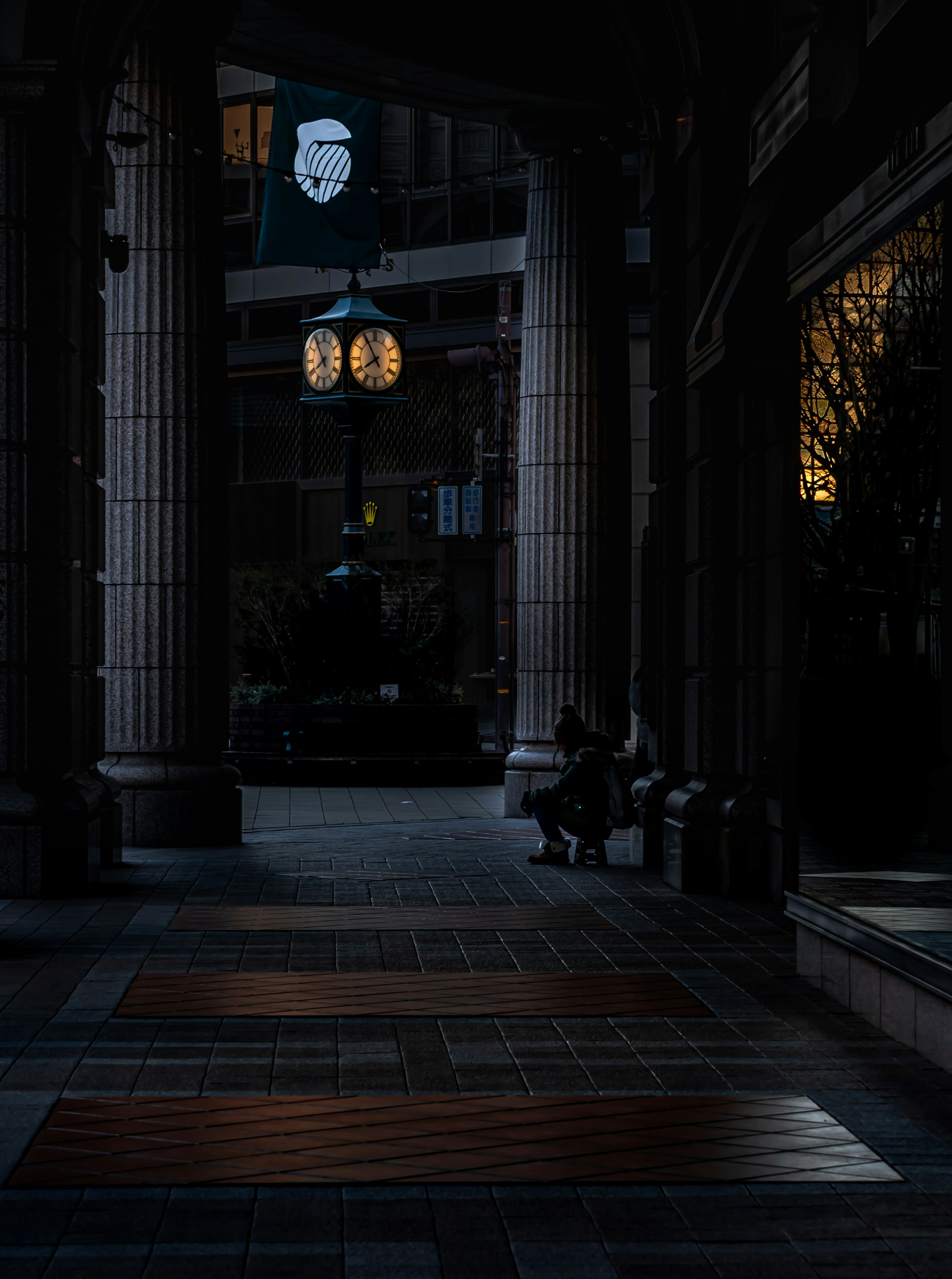 Twilight-lit stone arcade with street lamps and long shadows