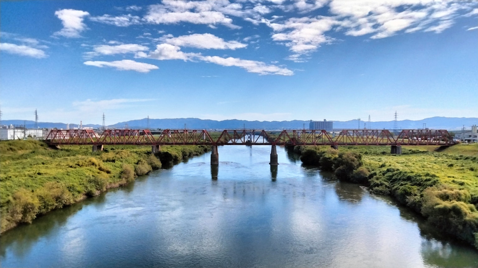 Un pont traversant une rivière avec une verdure luxuriante sous un ciel bleu clair
