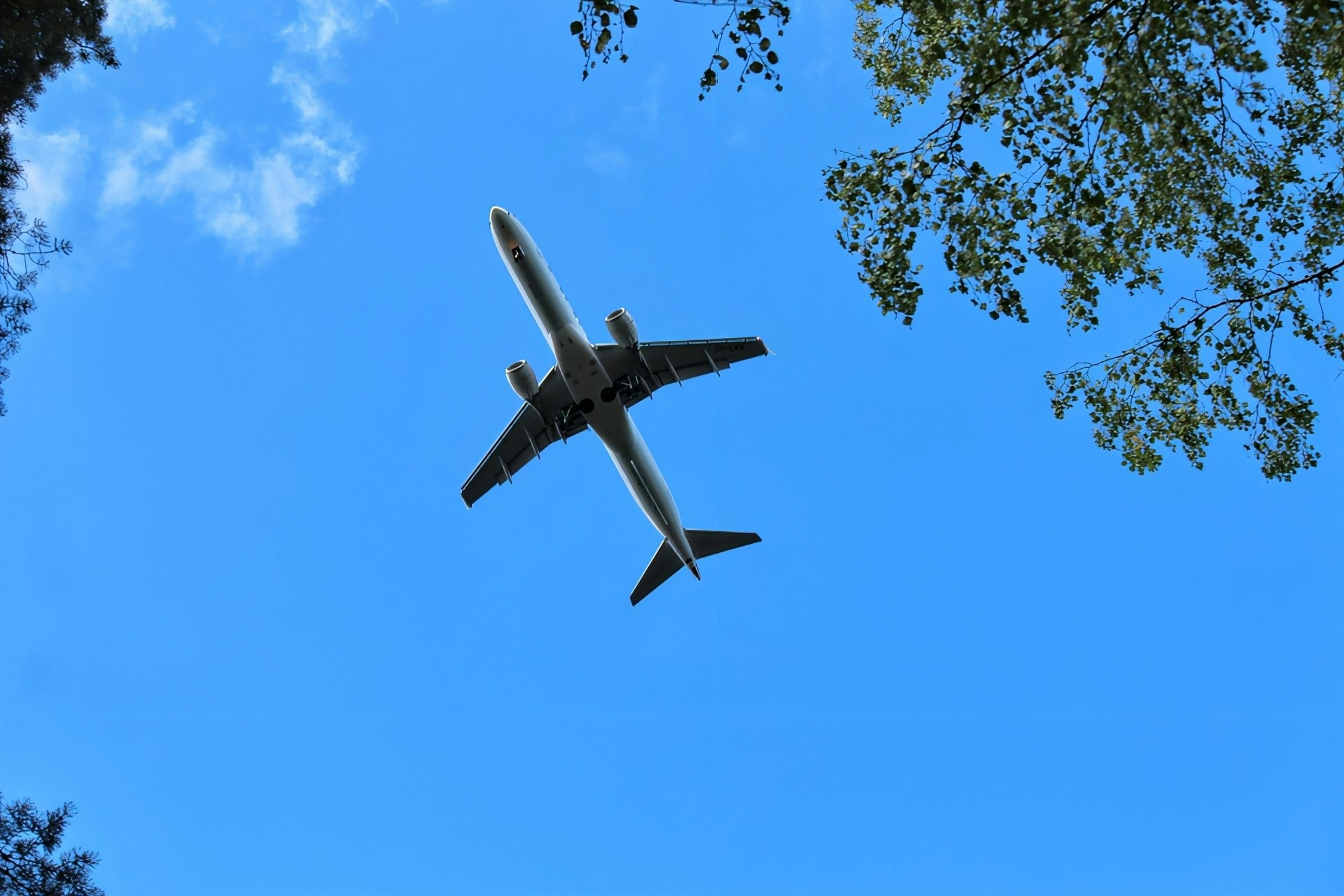 Airplane silhouette against a blue sky, looking up