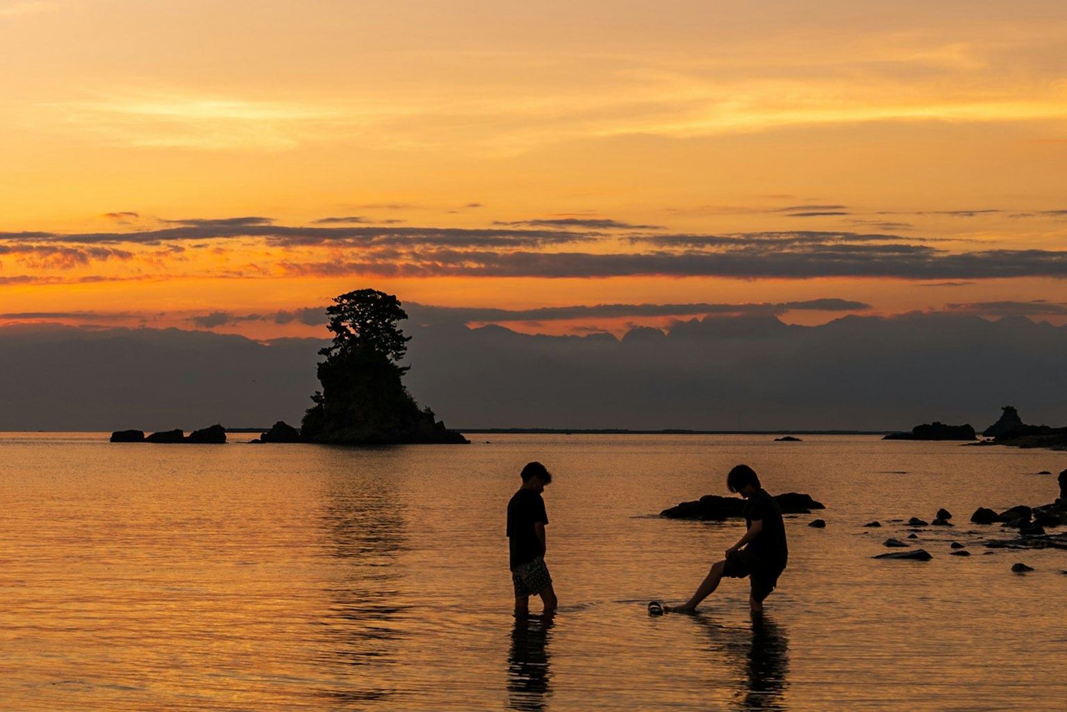 Bambini che giocano nel mare al tramonto con un'isola sullo sfondo