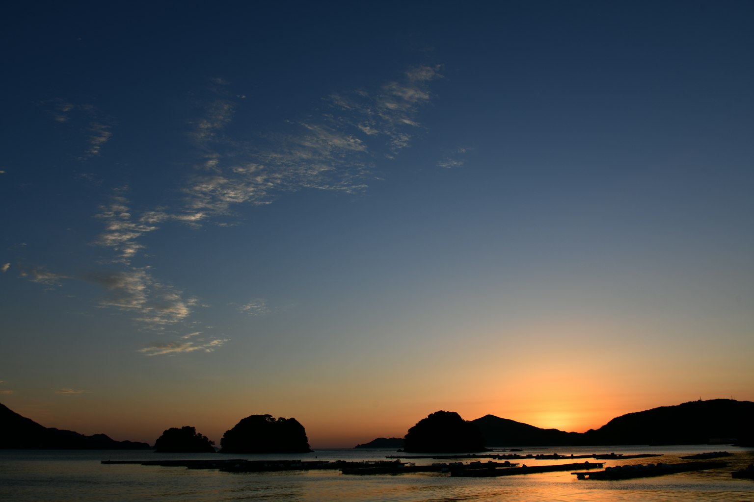 Scenic view of the sea and islands at sunset with a beautiful orange sun setting on the horizon
