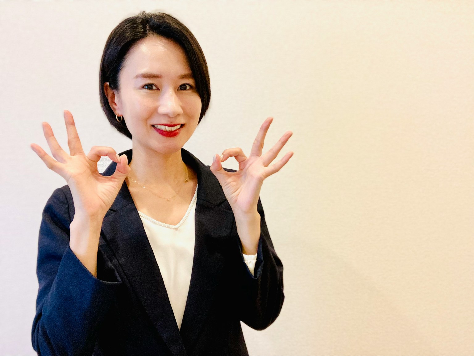 一位穿著西裝的女性用手做出OK手勢