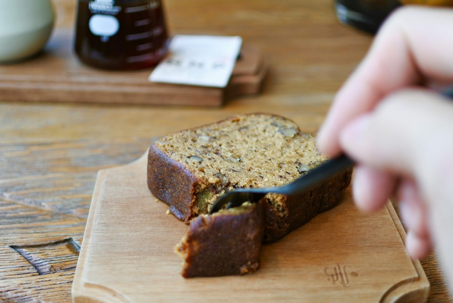 A slice of baked dessert being cut with a spoon held in hand
