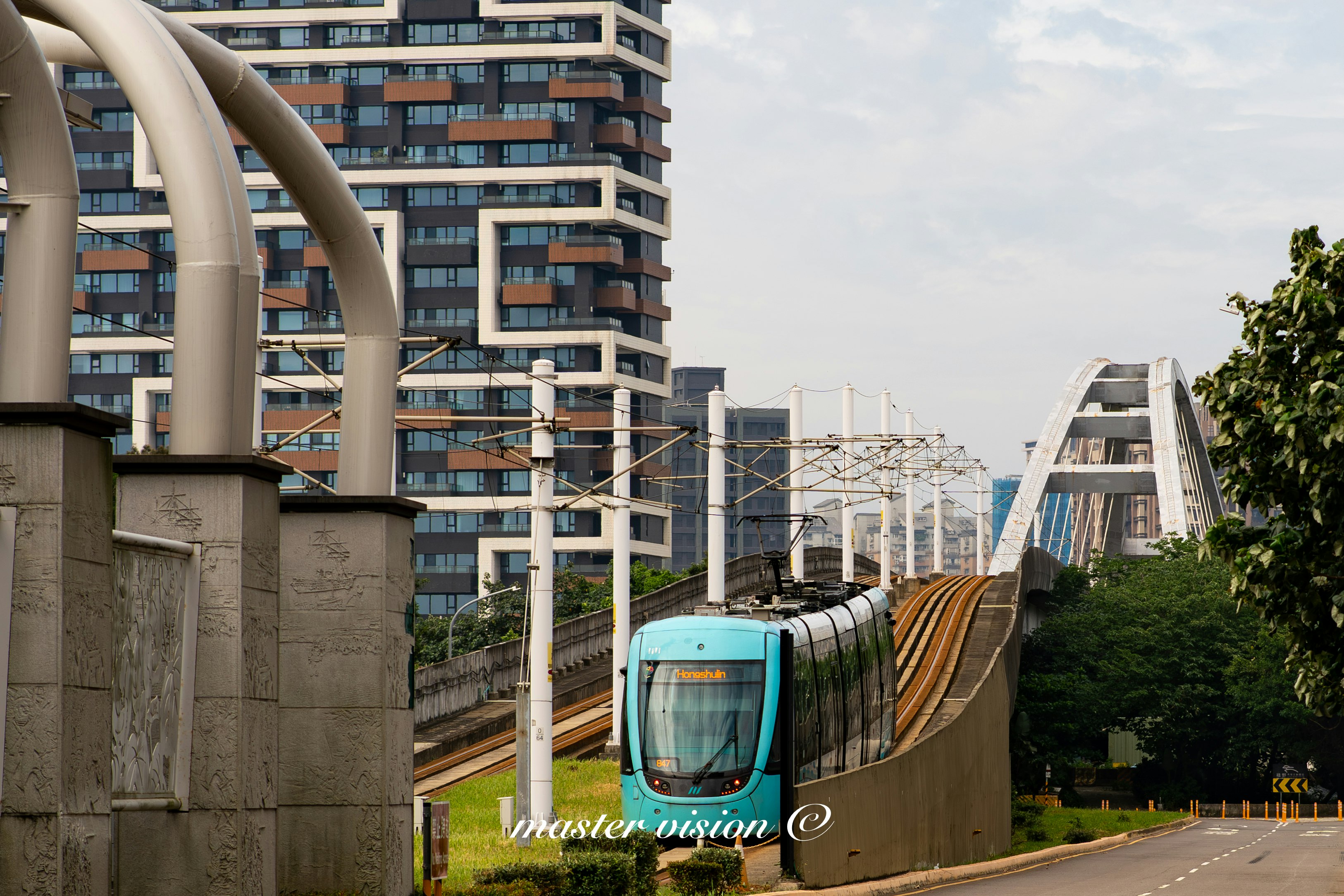 高層マンションと高架線路を走る青い電車のある都市風景