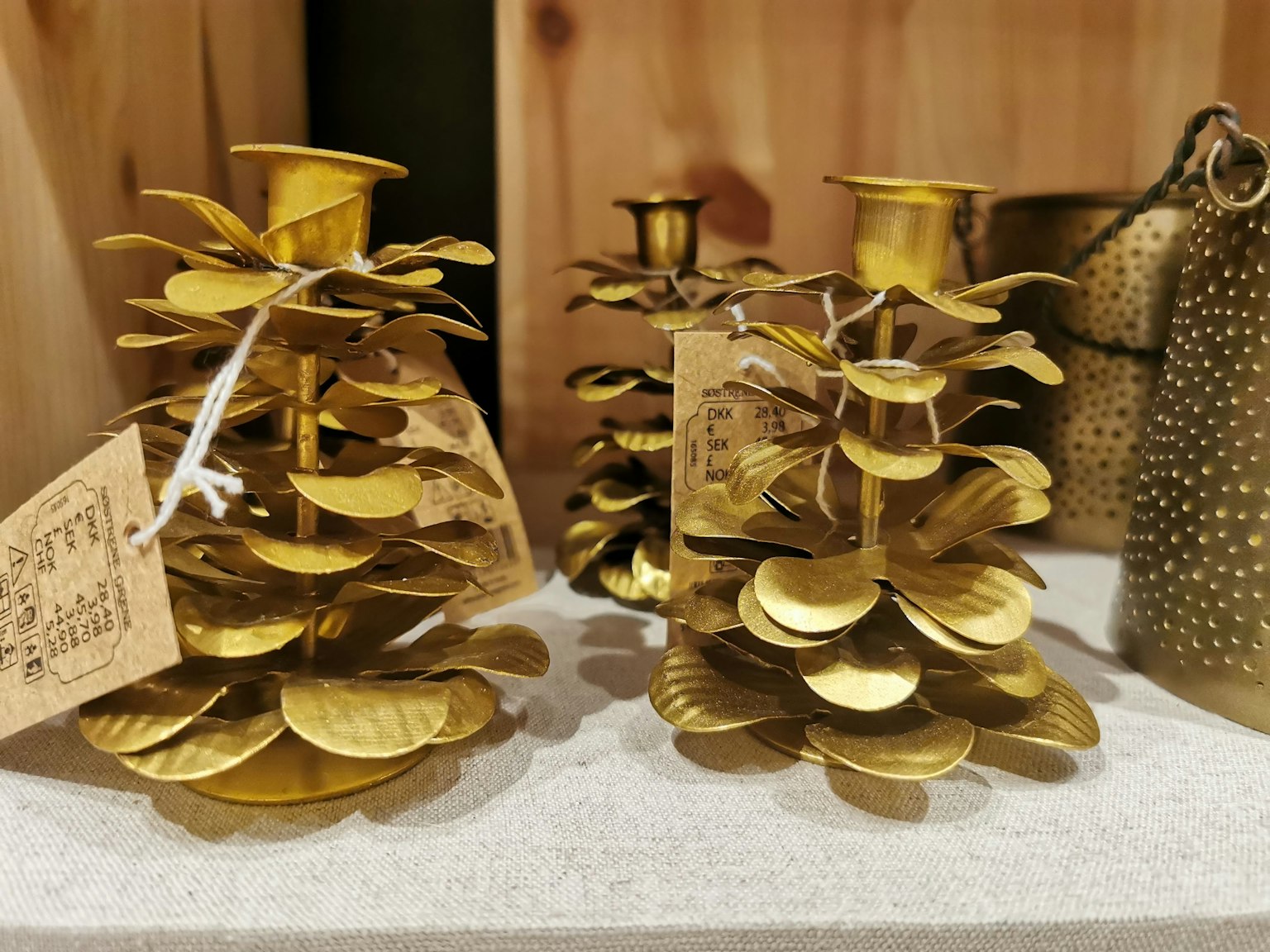 Deux porte-bougies dorés en forme de cône de pin avec des feuilles décoratives