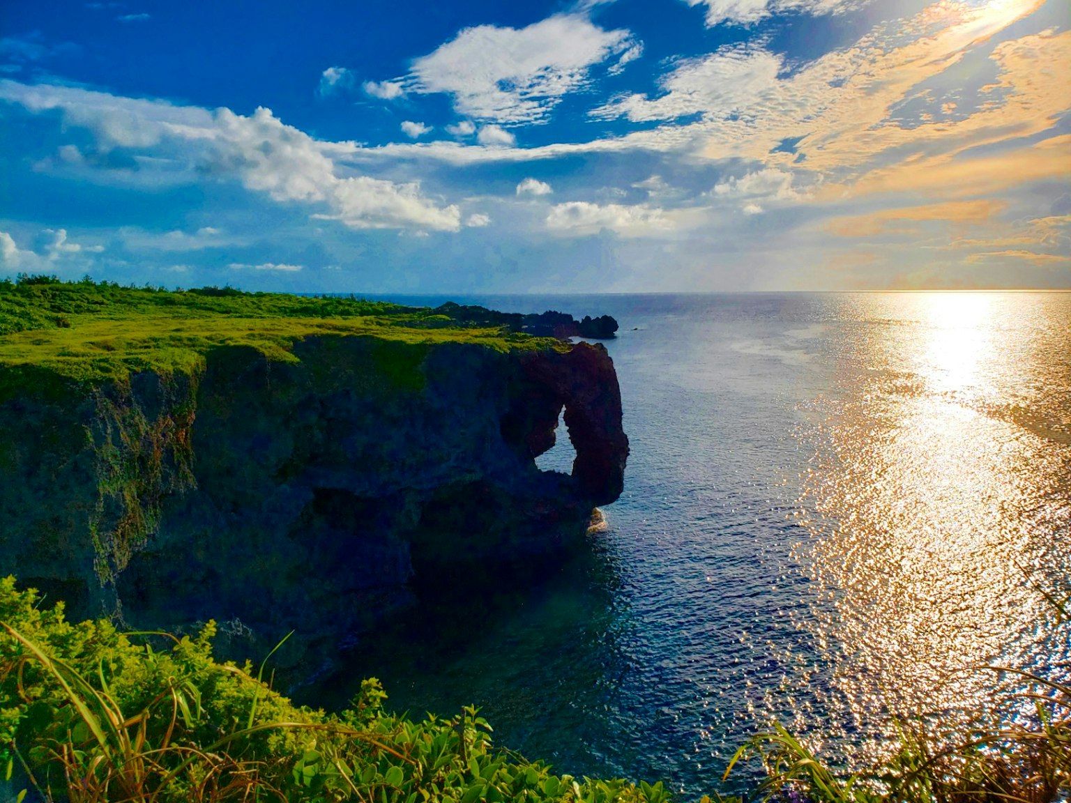 Pemandangan indah tebing hijau dikelilingi langit dan laut biru Cahaya matahari memantul di atas air