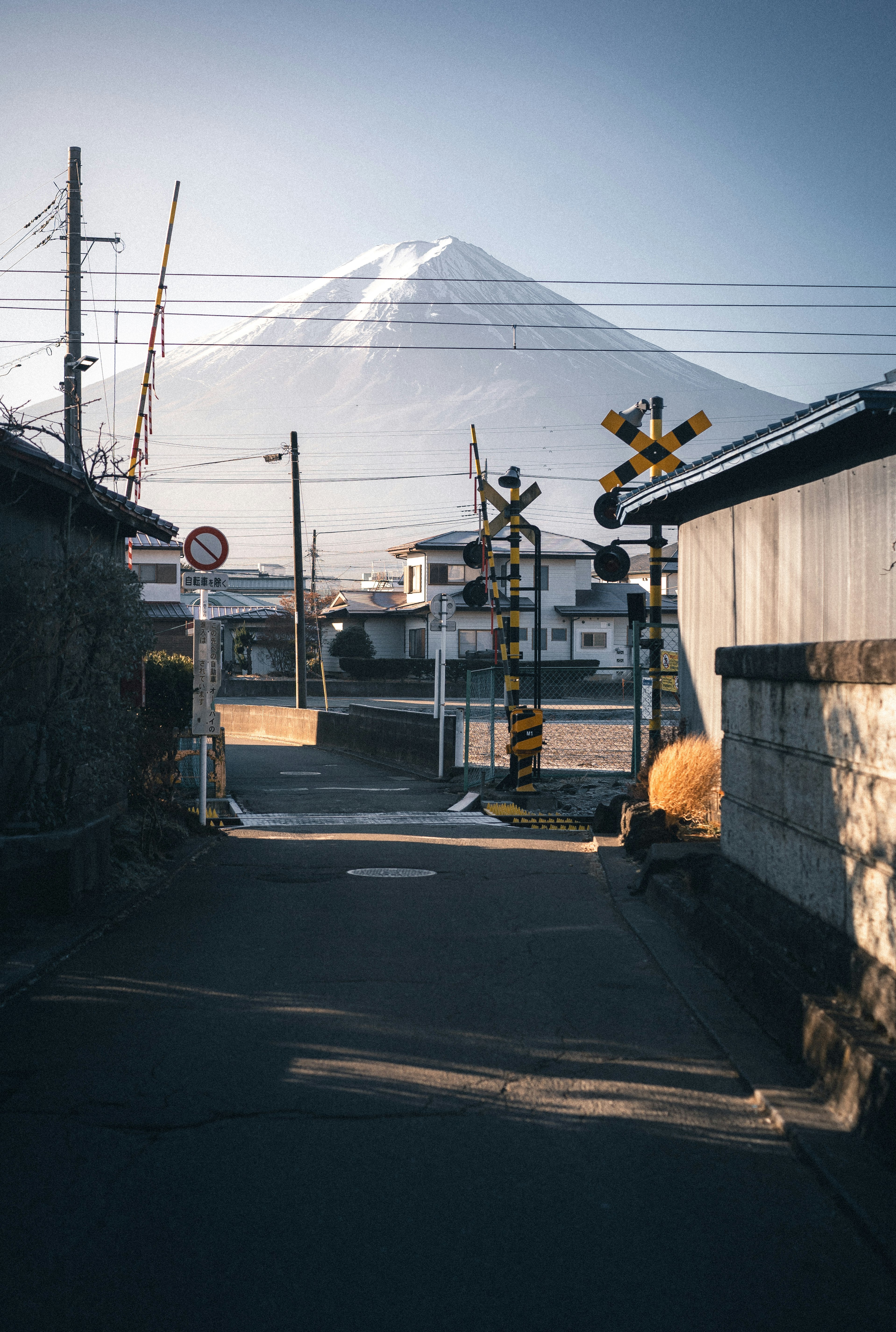 踏切のある路地と遠くに見える山のシルエット