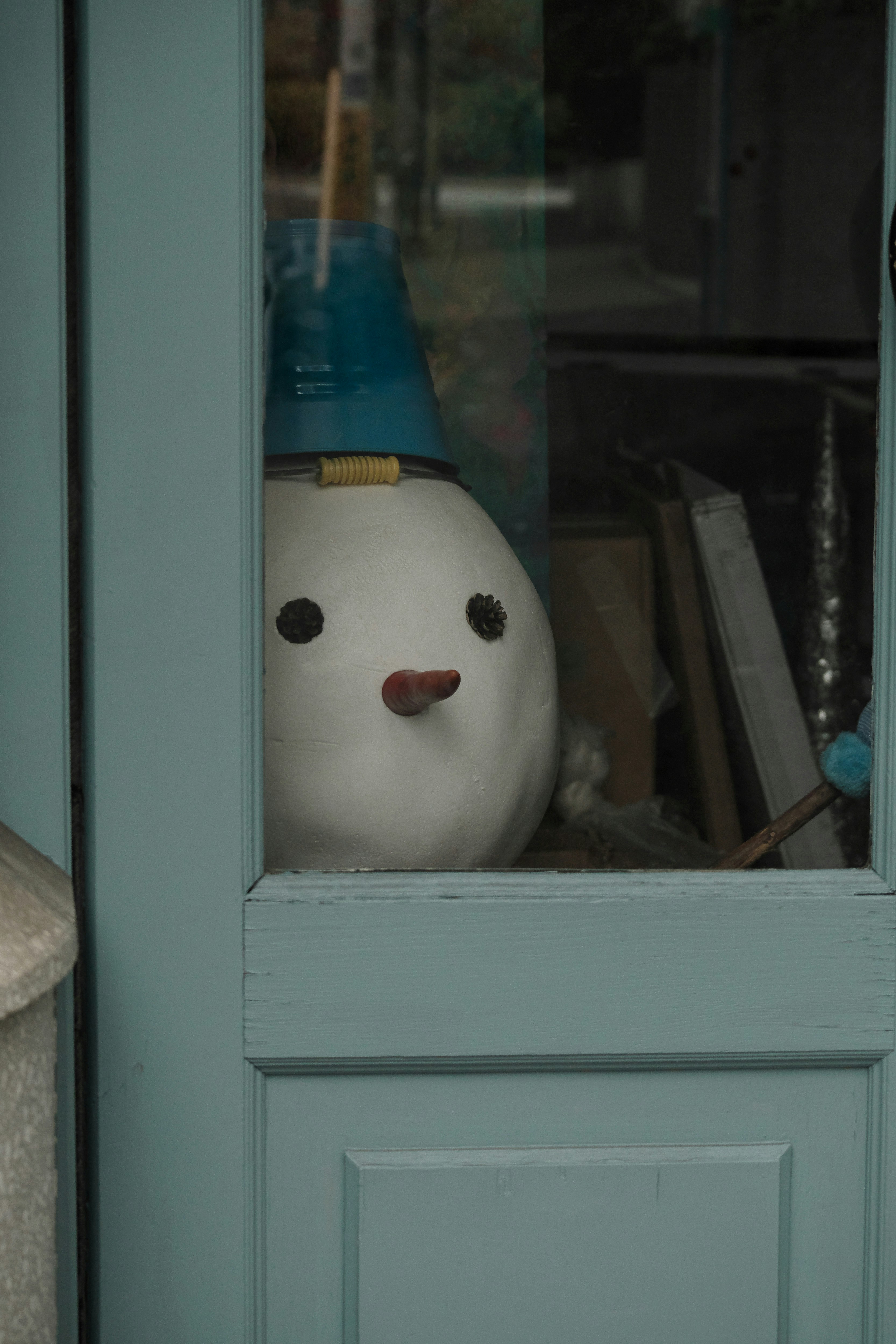 A snowman looking out from a window onto a cityscape