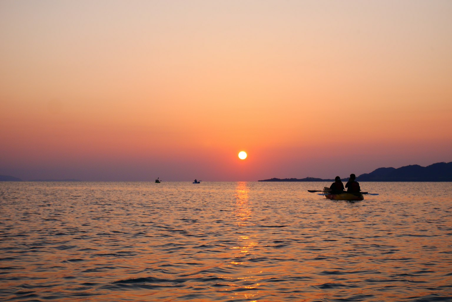 Deux personnes dans un bateau au coucher de soleil sur l'océan