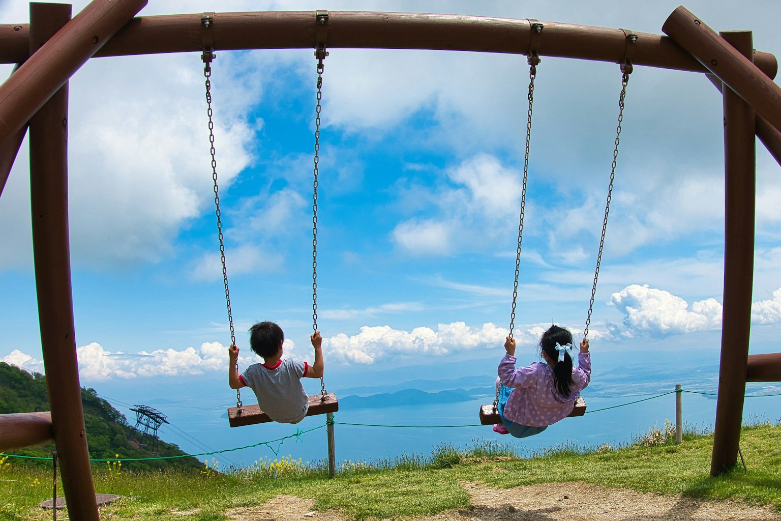 Enfants se balançant sous un ciel bleu avec des nuages