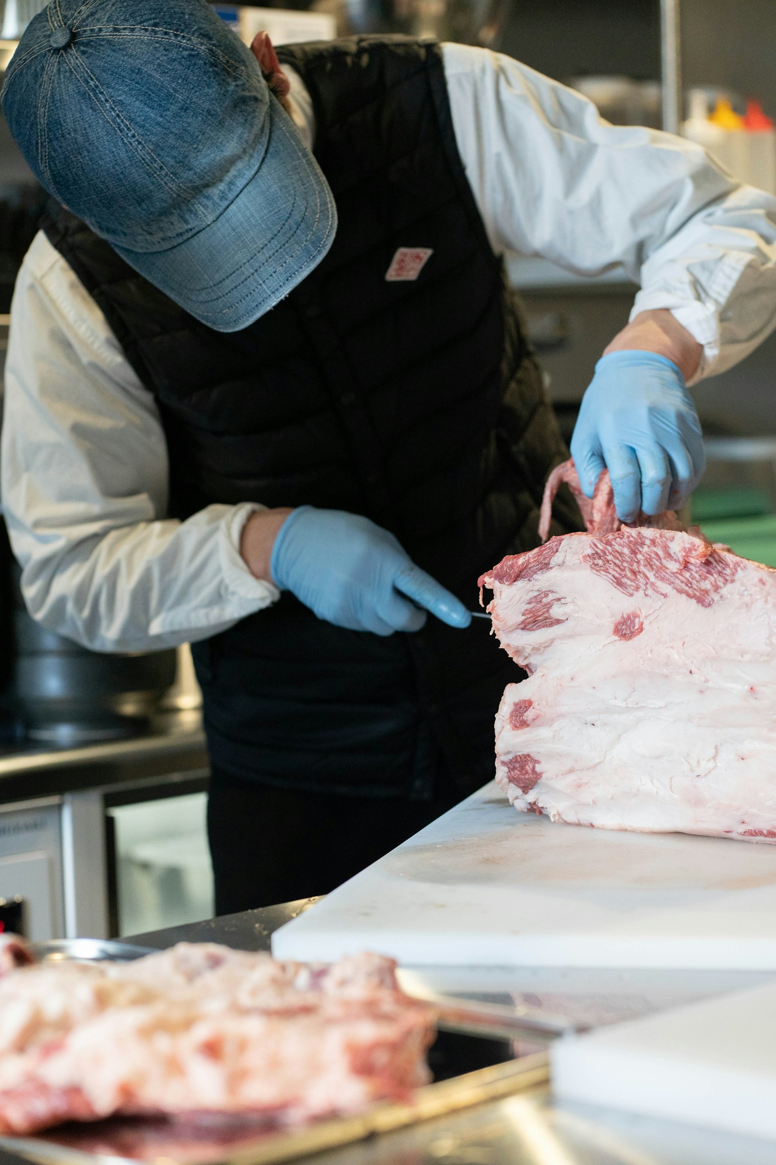 Person cutting meat with gloves in a kitchen setting