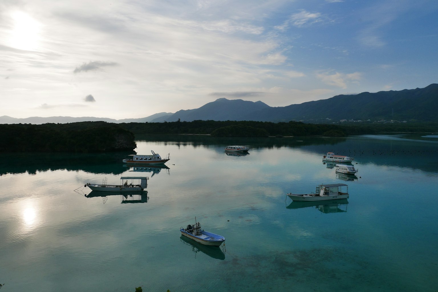 小船漂浮在平静的海面上，周围是自然景观