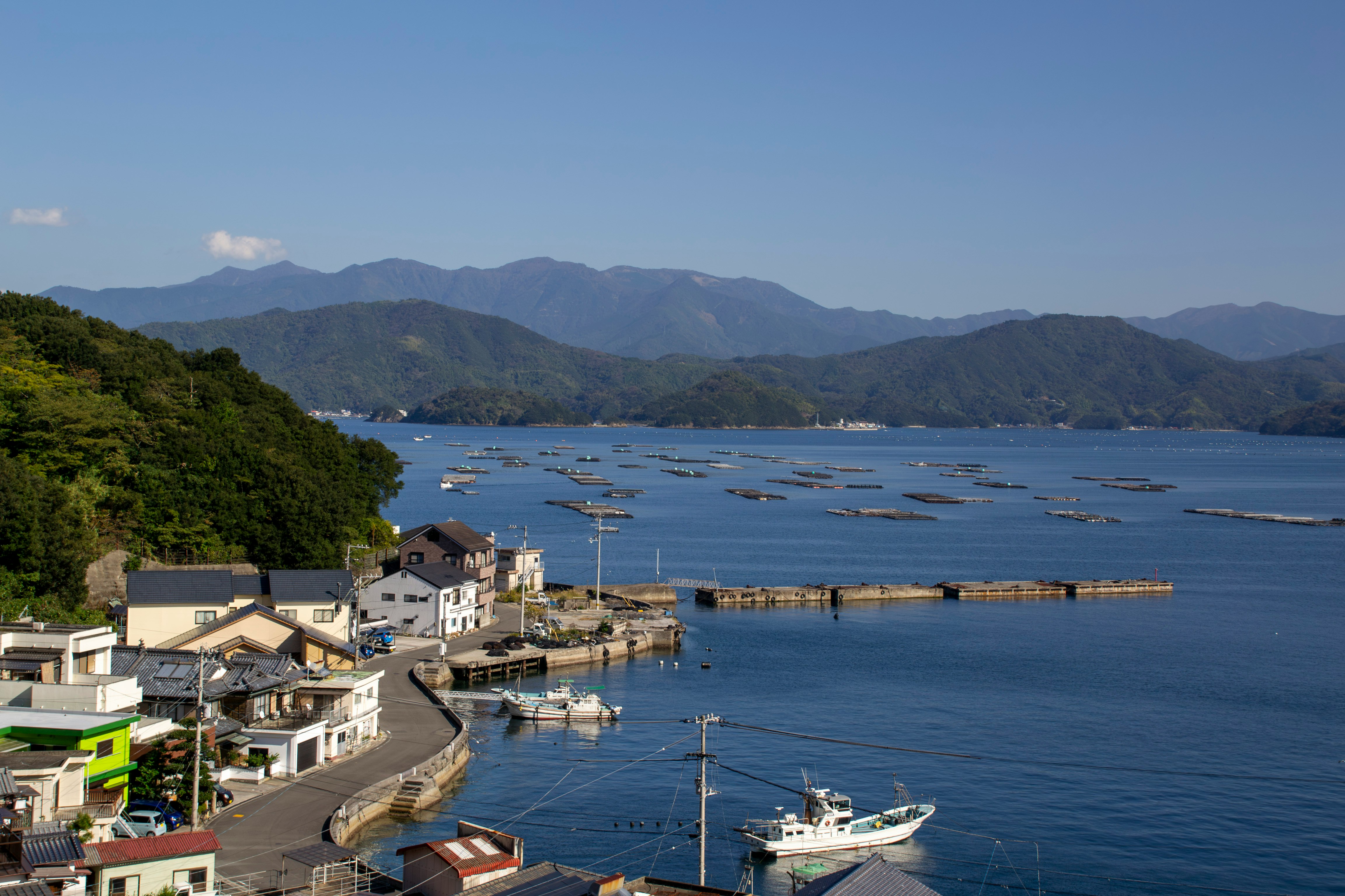 宇和島市の港と海に浮かぶ漁船、山並みの風景