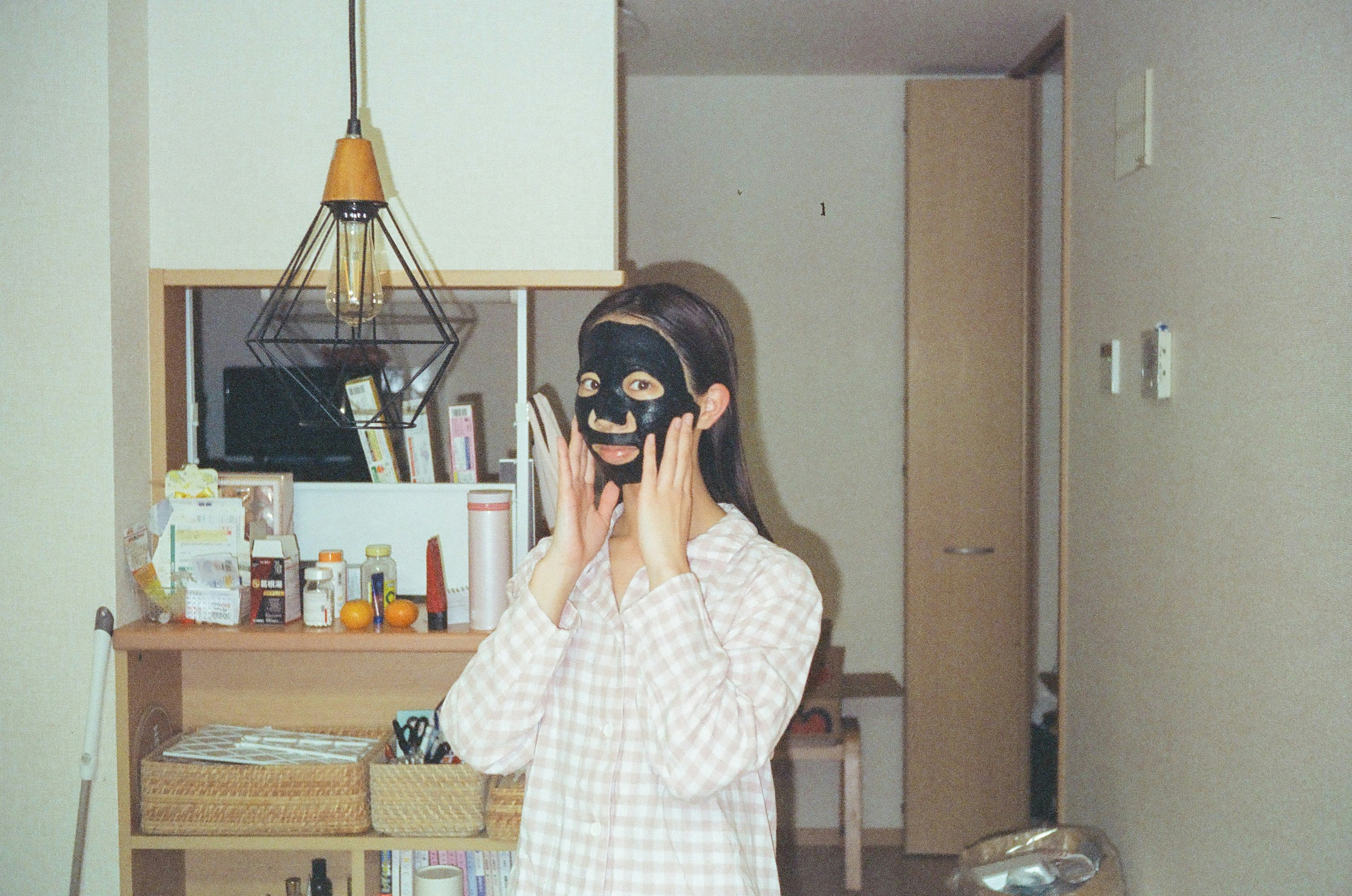 マスクをした女性が部屋でポーズをとる