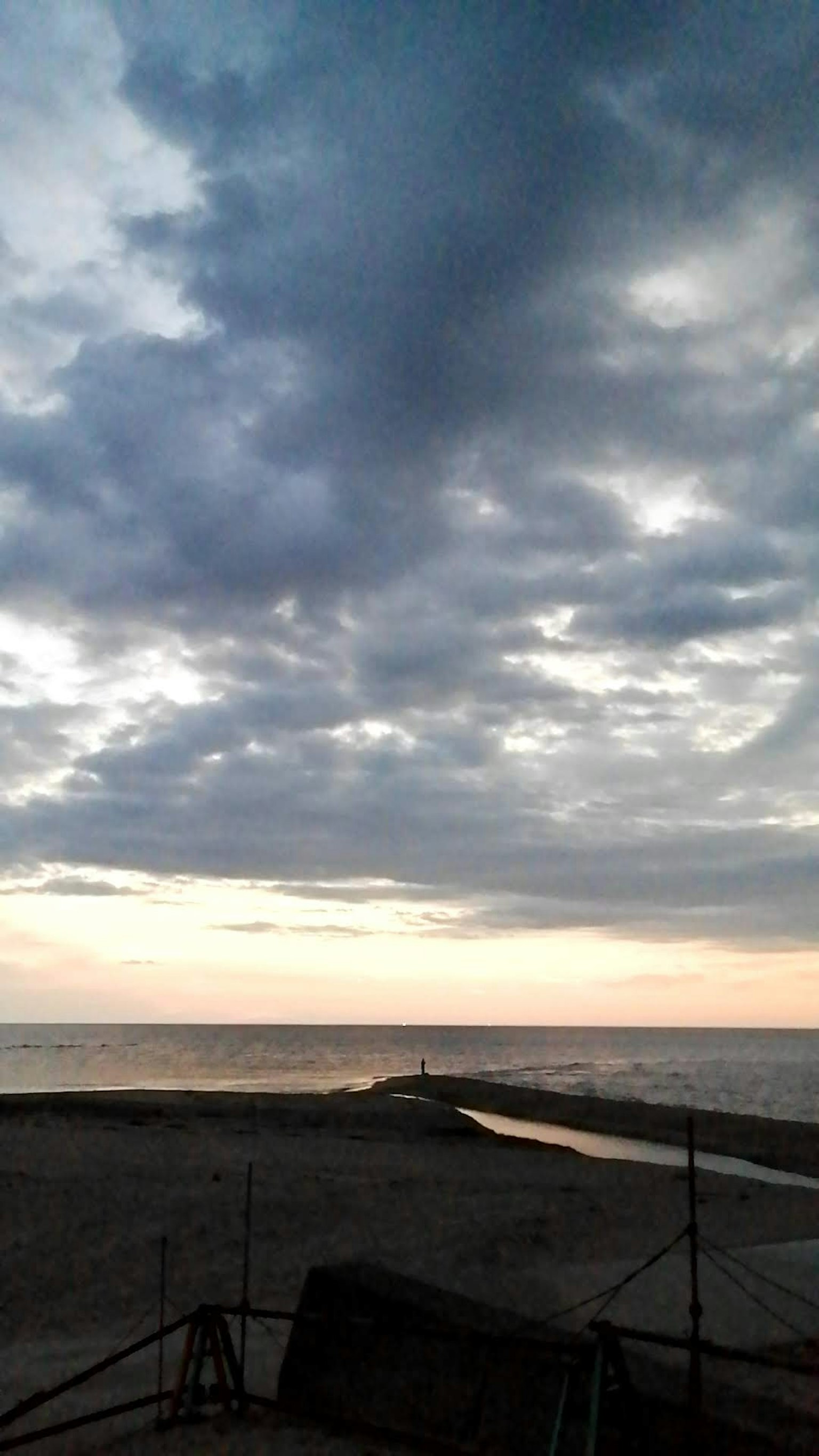 Pemandangan laut dengan langit berawan dan nuansa matahari terbenam