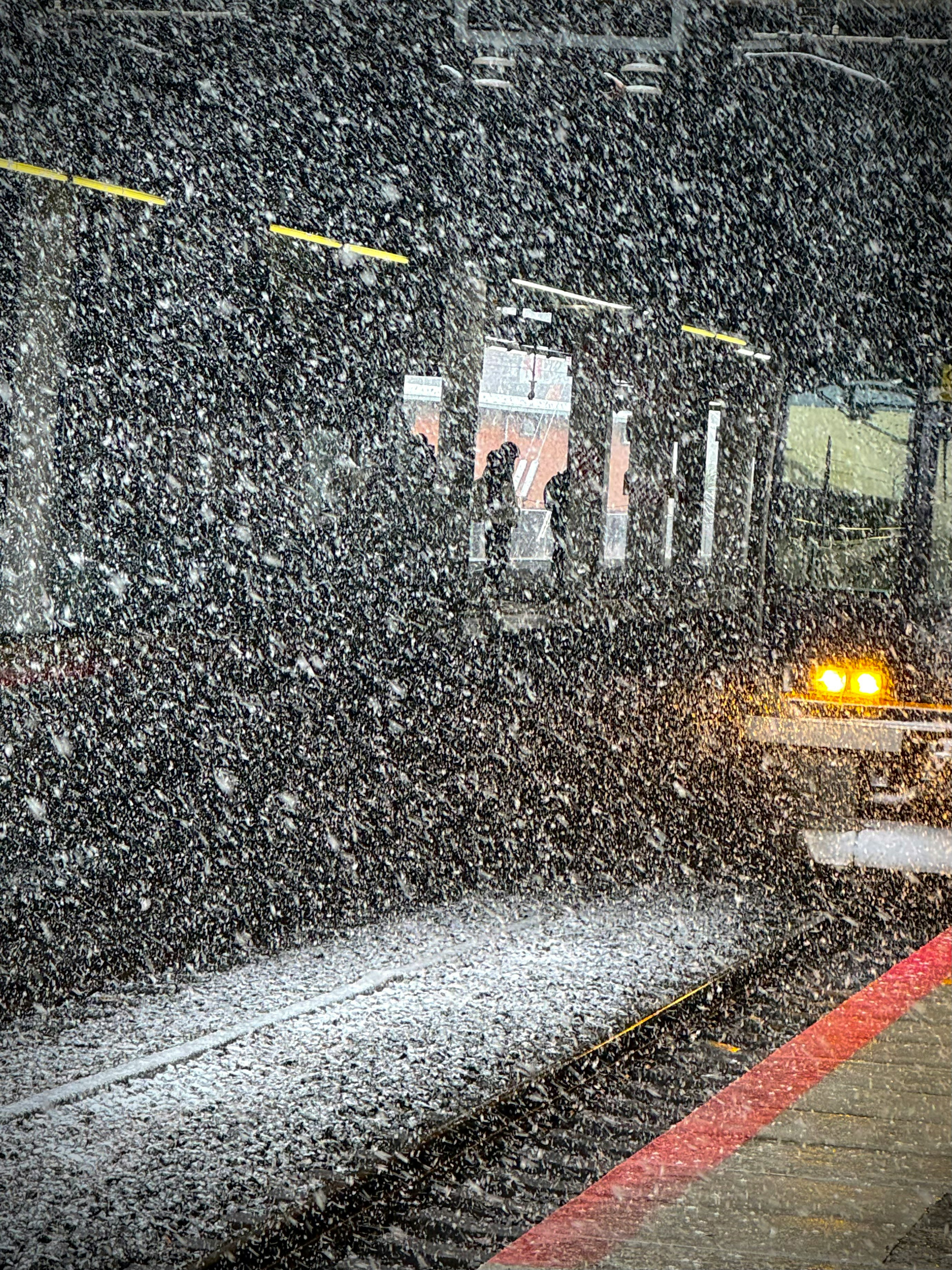 雪が降る駅のプラットフォームで列車が待機している風景