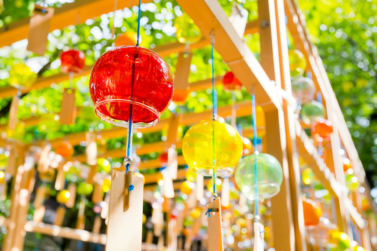 Campanas de viento coloridas colgando de una estructura de madera rodeada de vegetación