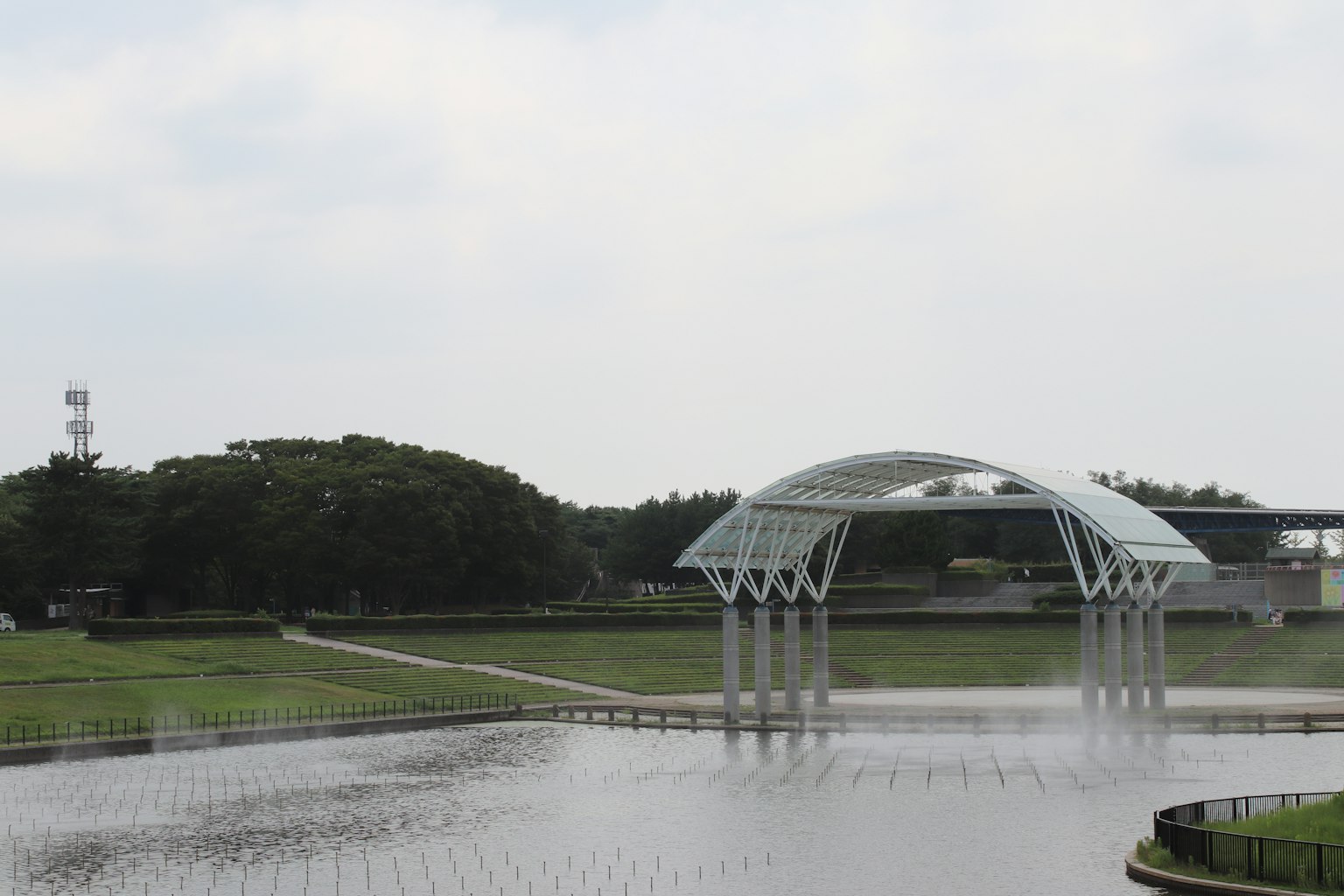 現代白色拱橋橫跨寧靜水域，周圍是綠色景觀