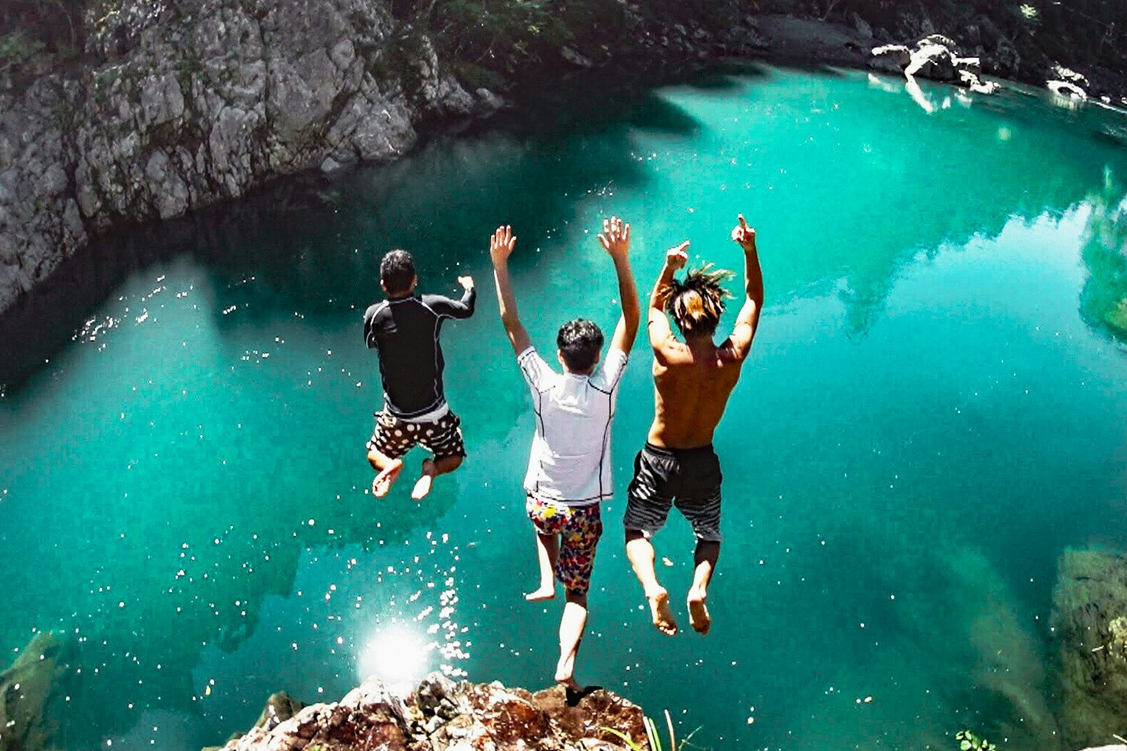 energetic moment of people jumping into a turquoise river