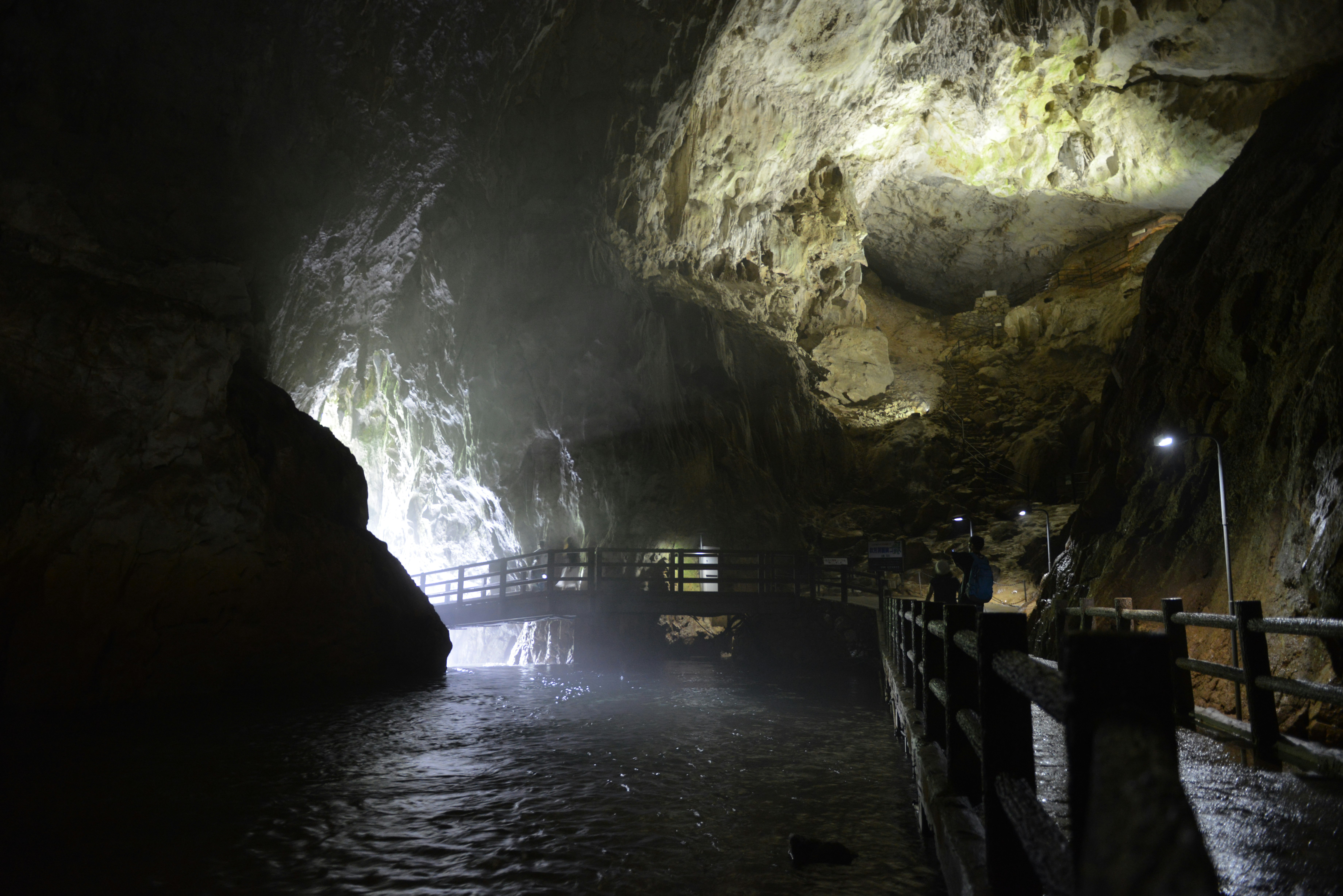 lit walkway beside a waterfall inside a cave