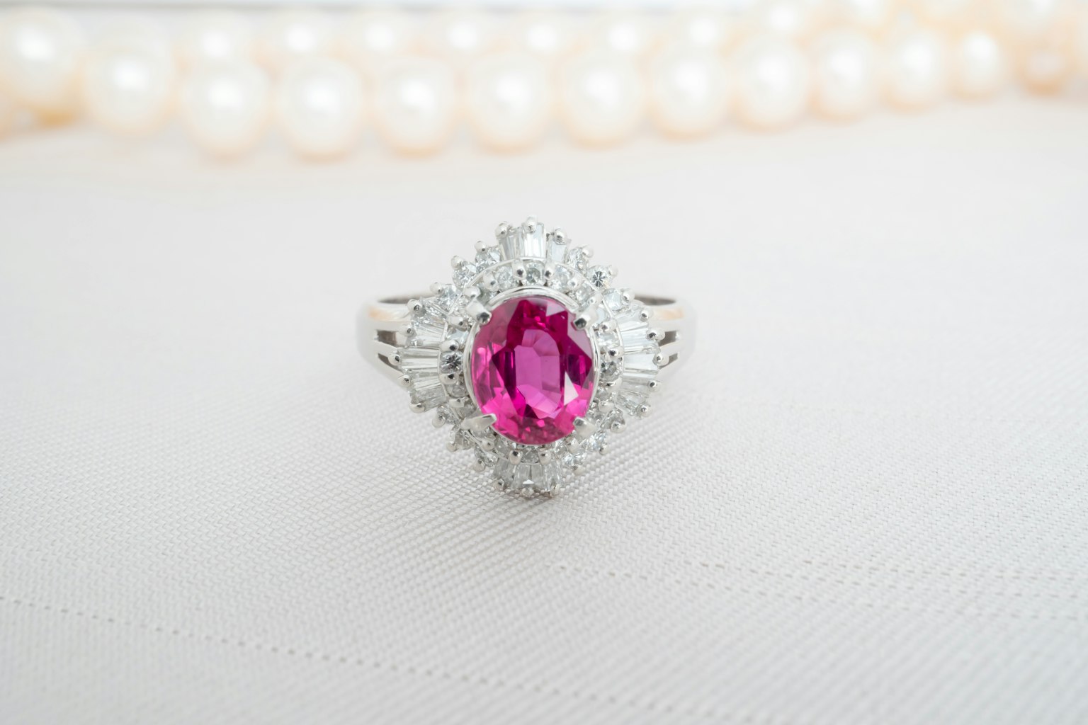 Beautiful ring featuring a central pink gemstone and a pearl necklace