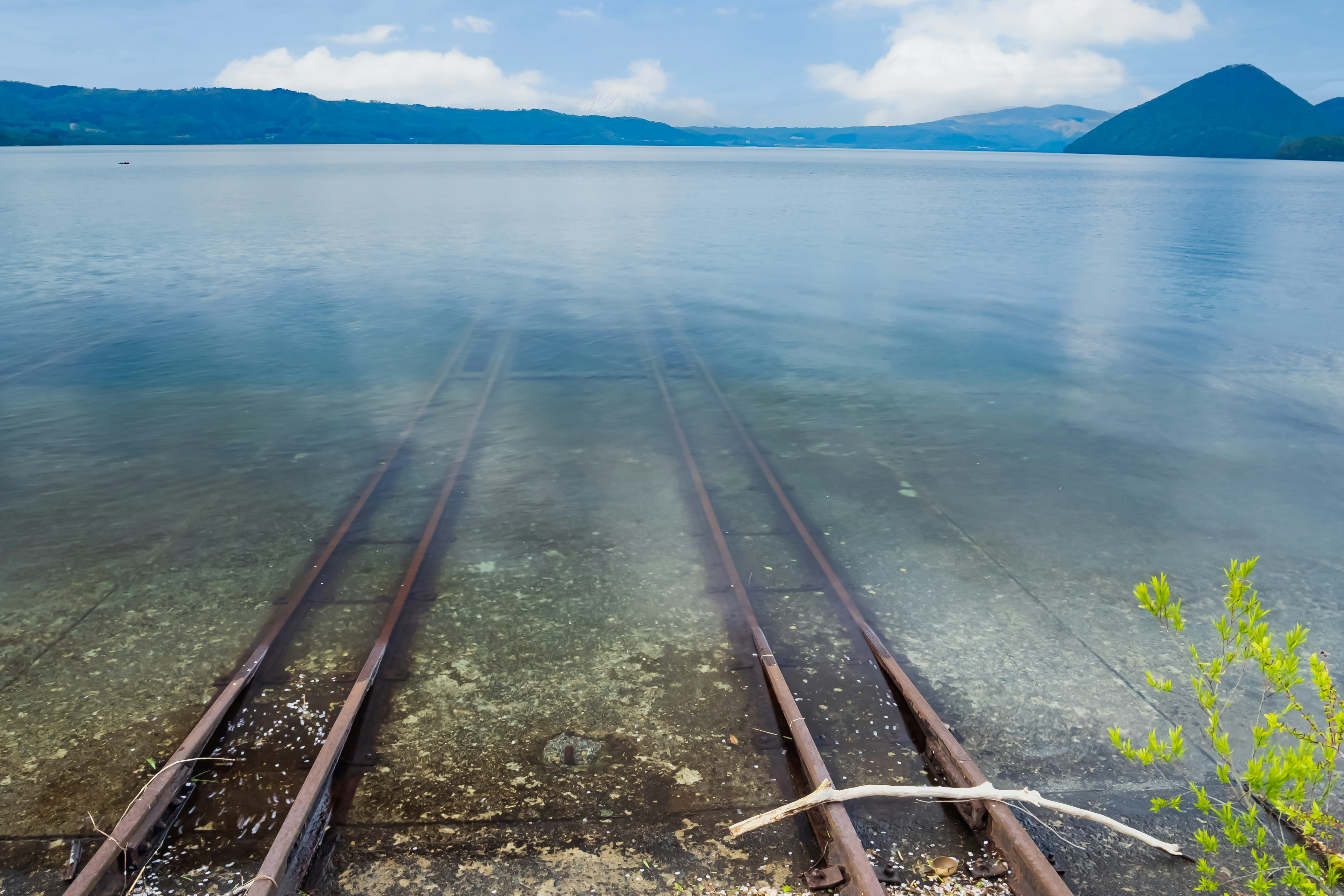 湖畔に伸びる線路と遠くの山並み