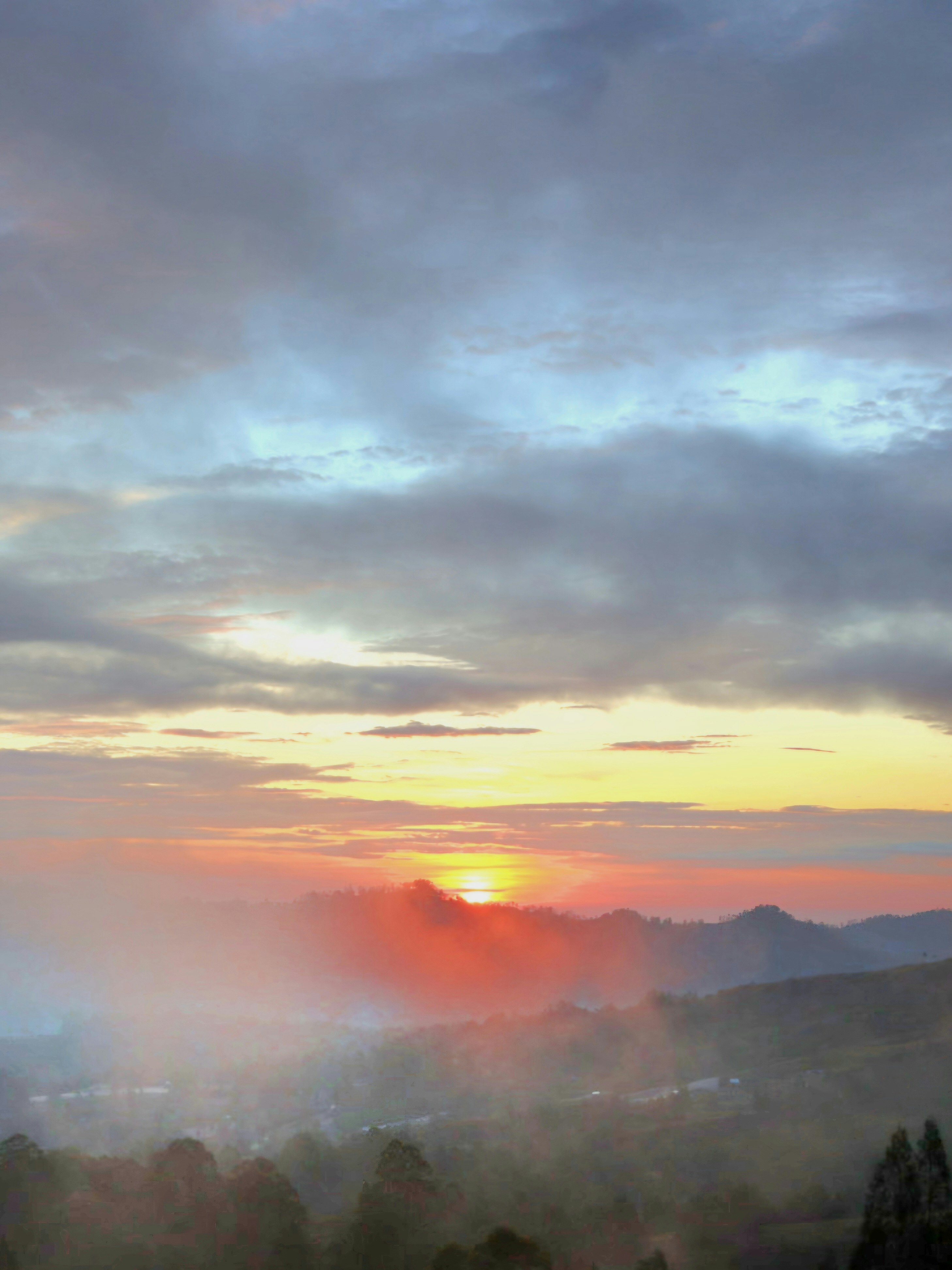 neblige Berglandschaft mit Sonnenaufgangsstrahlen