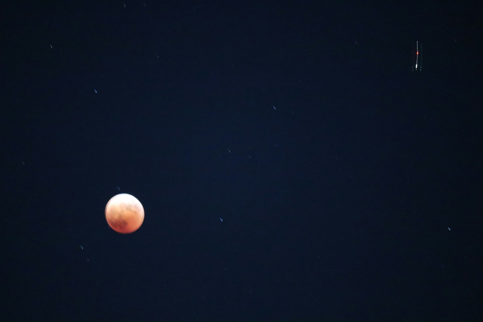 Una luna roja contra un cielo oscuro lleno de estrellas
