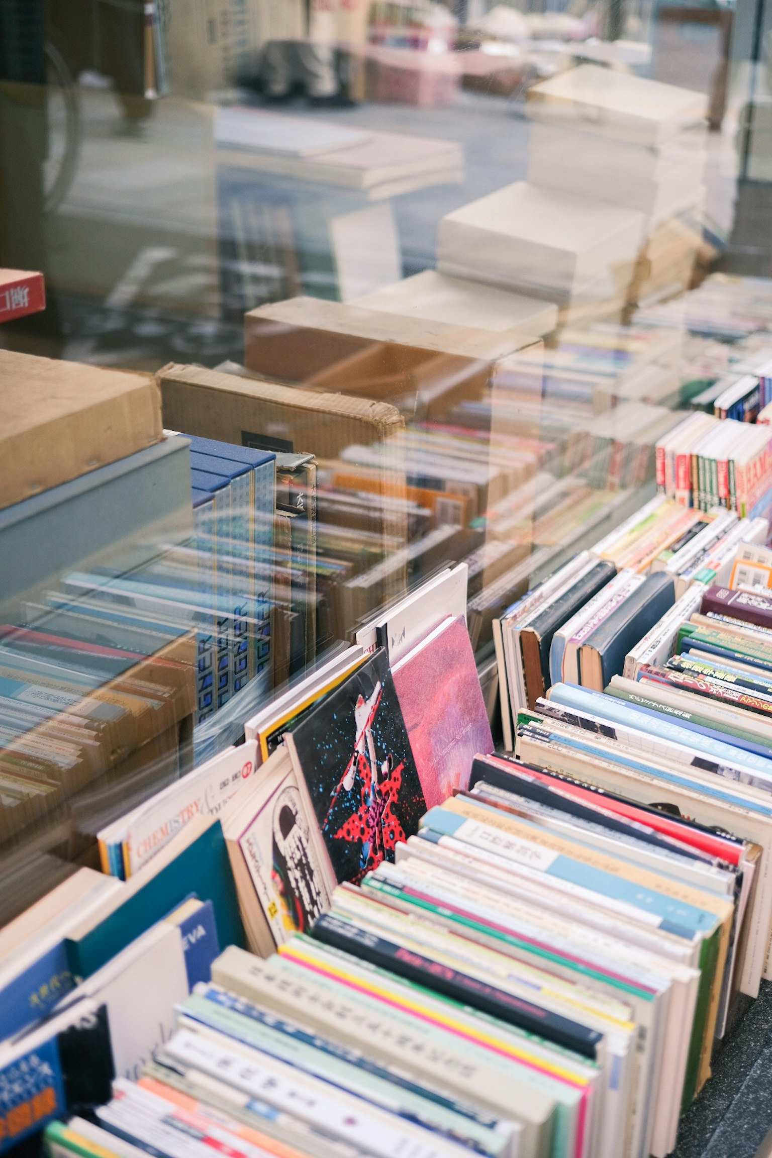 Exterior view of a bookstore window featuring a variety of books in different colors and designs