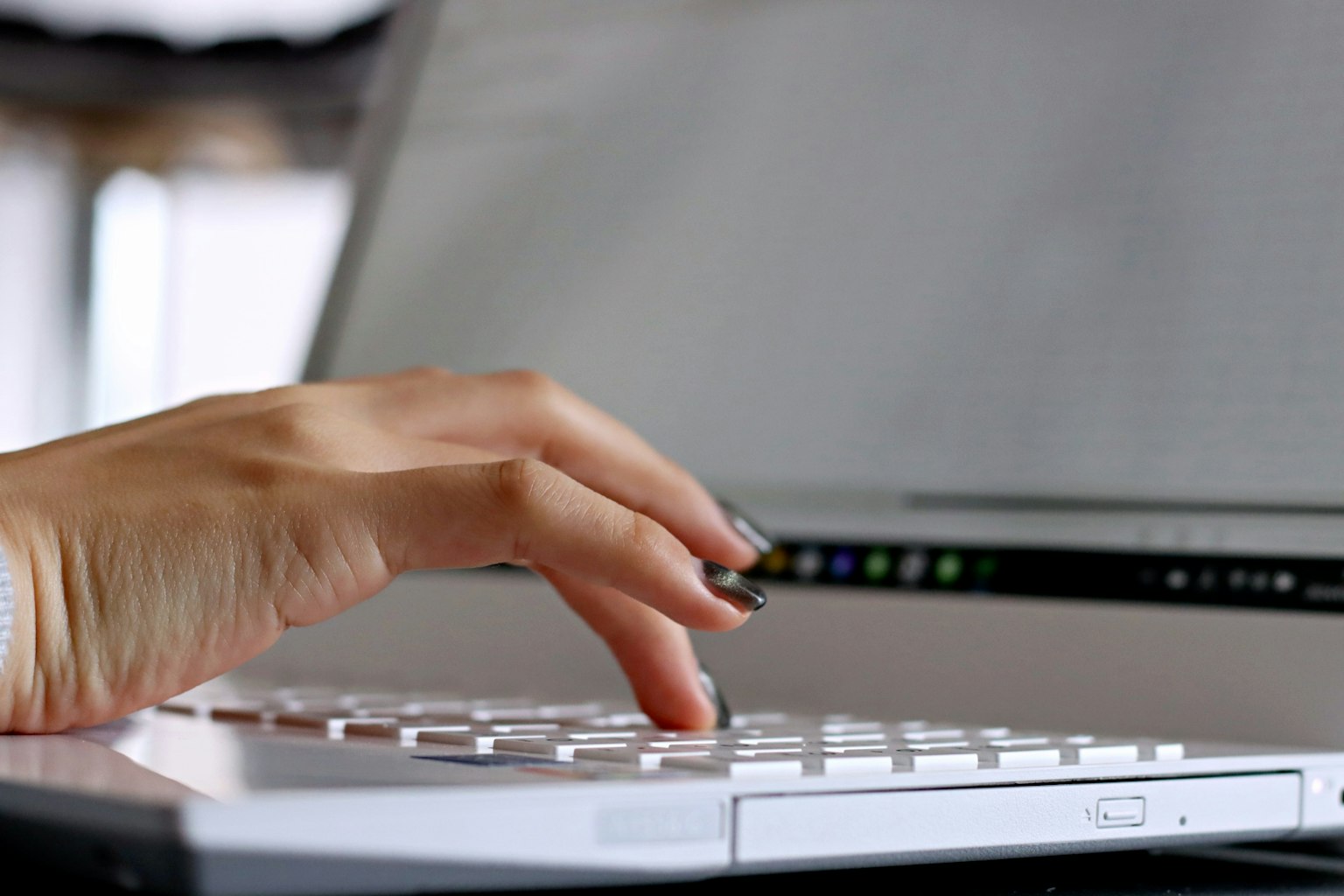 Primer plano de una mano escribiendo en un teclado de computadora portátil