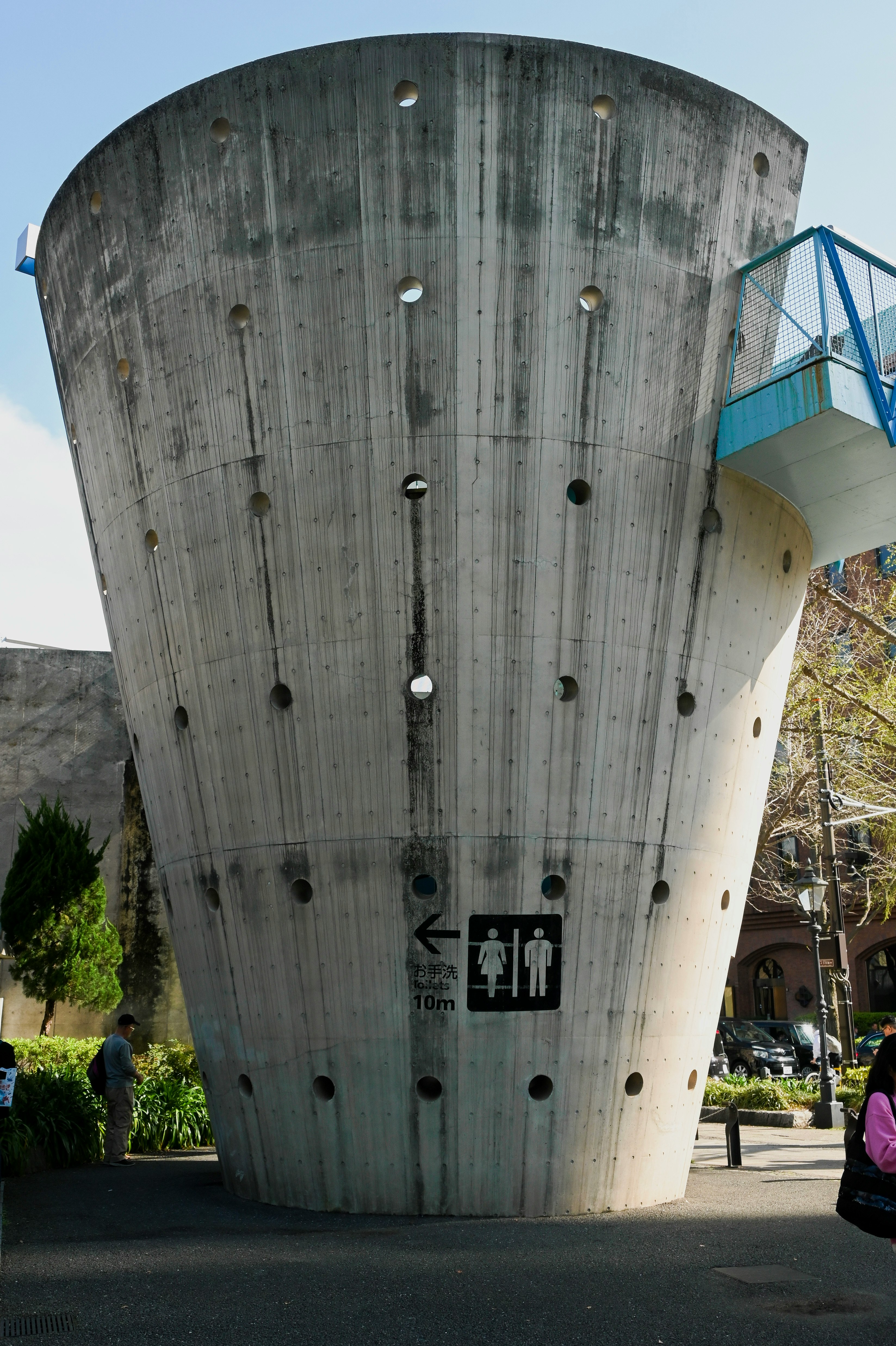 grand bâtiment en béton cylindrique avec des personnes sur une place