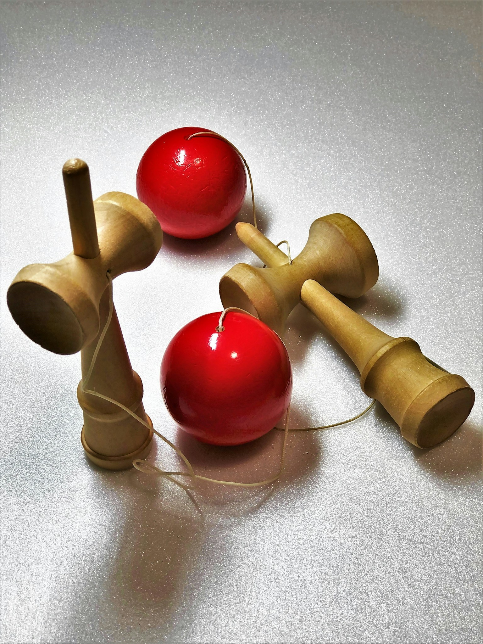 Immagine che presenta palline rosse e giocattoli kendama in legno disposti artisticamente