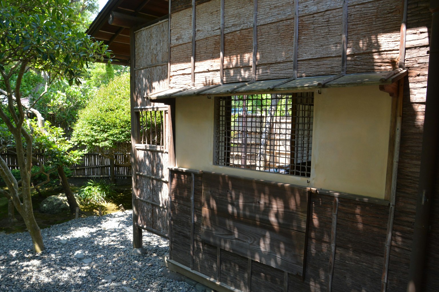 Vue extérieure d'un bâtiment japonais traditionnel entouré de verdure avec des murs en bambou et une fenêtre