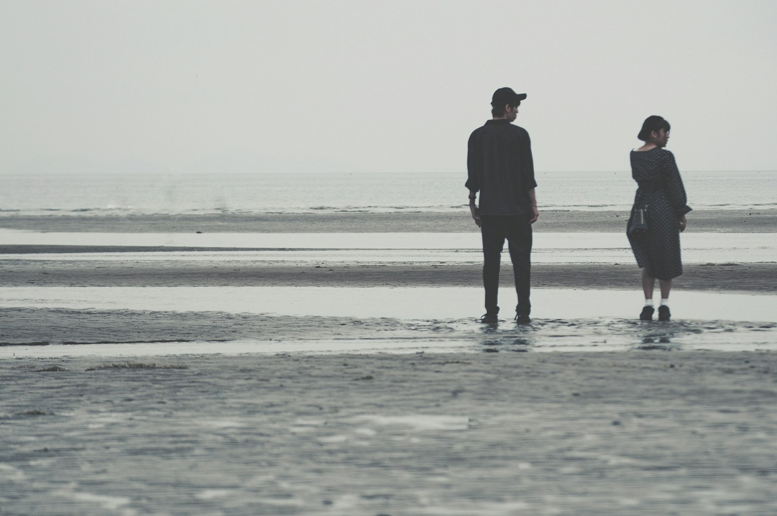 เงาของคนสองคนยืนอยู่ที่ชายหาด