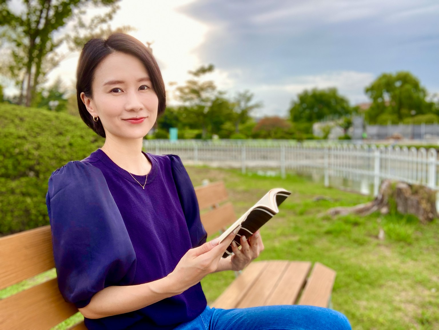 一位坐在公園長椅上閱讀書籍的女性