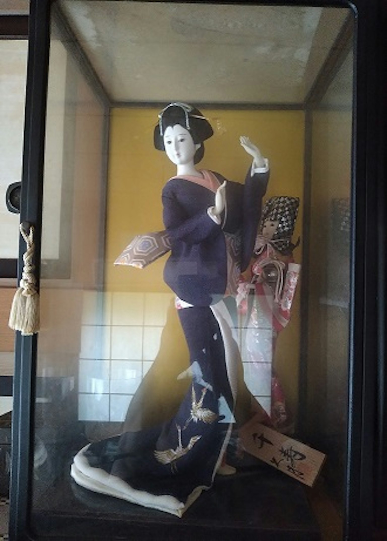 Una bella bambola giapponese in kimono viola esposta in una teca di vetro