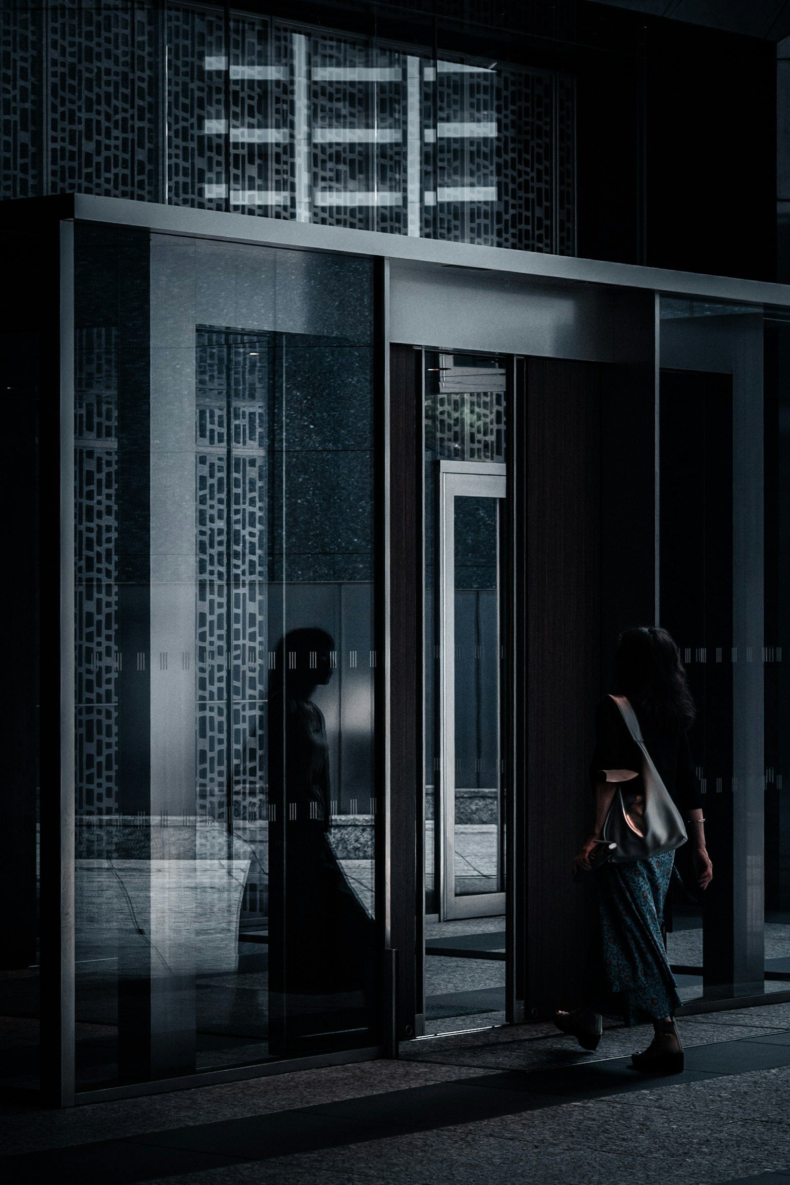 暗い背景にガラスのドアを通り抜ける女性のシルエット
