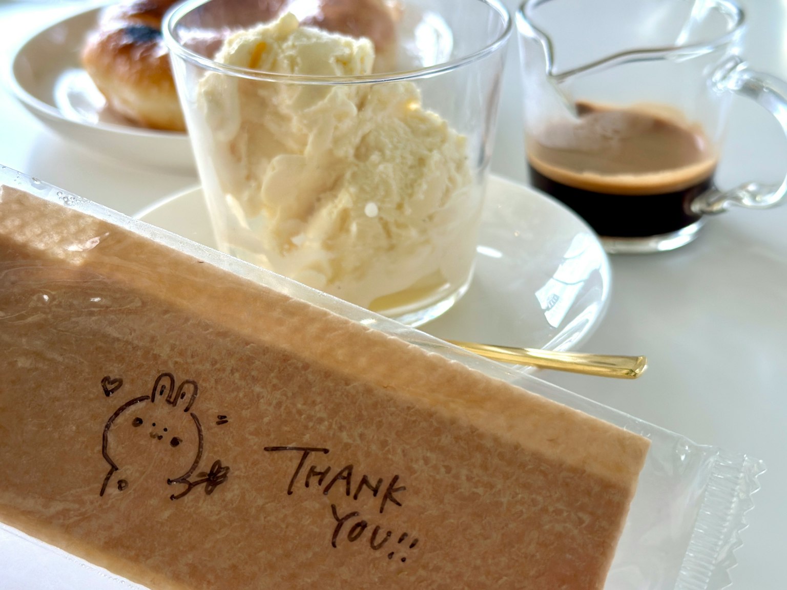 Dessert with cream in a glass and coffee on a table featuring a thank you message